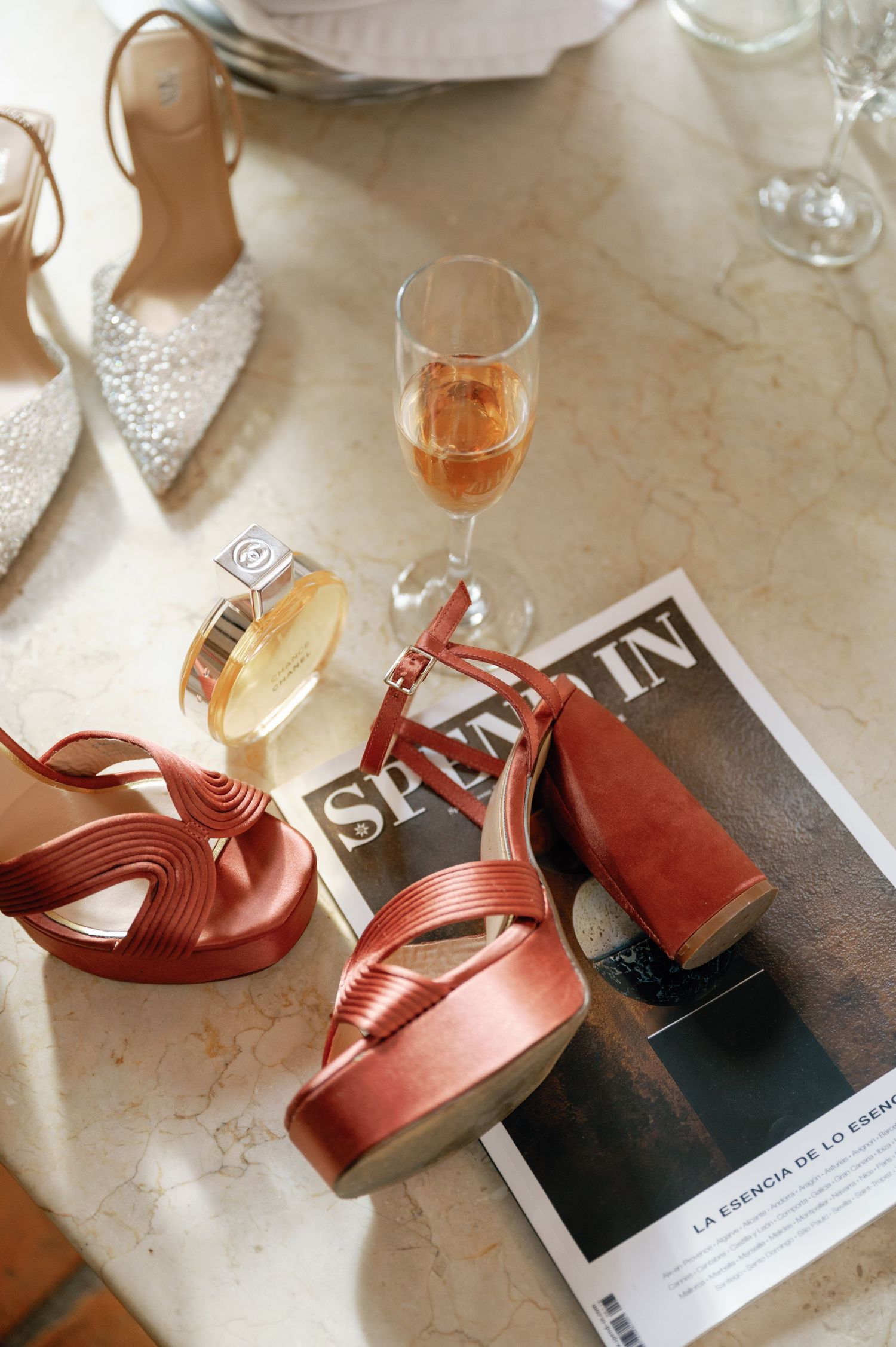 Multiple wine glasses filled with rose wine sit on a marble countertop with warm lighting and pink reflections.