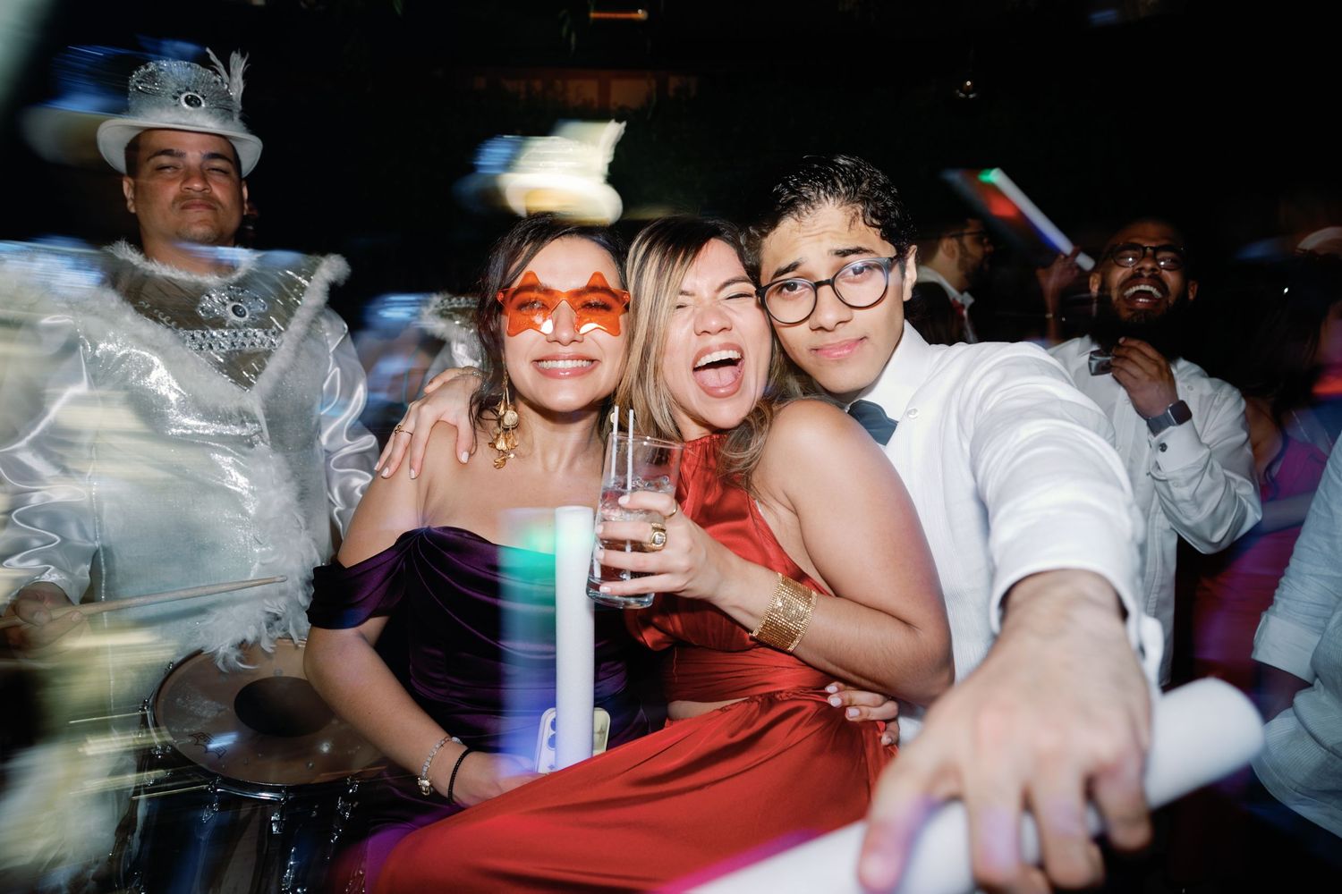 People dancing and socializing at a crowded nightclub with colorful lighting and drinks.