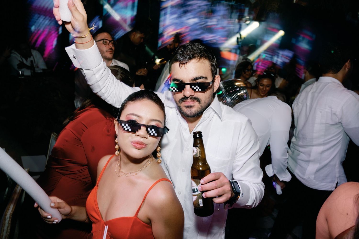 Lively dance floor scene at a wedding reception with colorful lighting and party atmosphere.