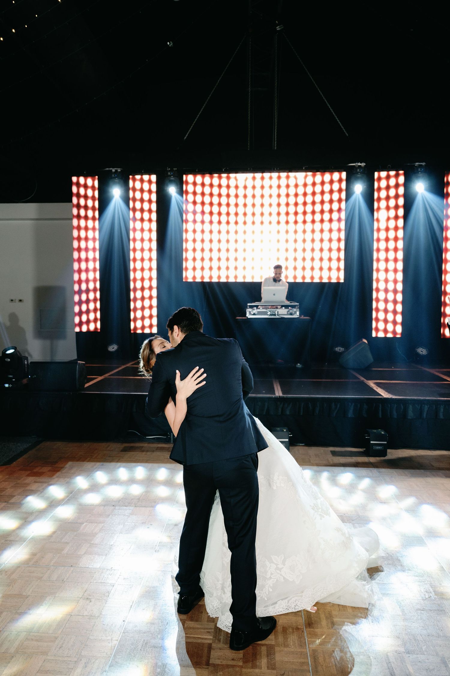 A couple shares an intimate slow dance on a spotlit dance floor at their wedding reception.