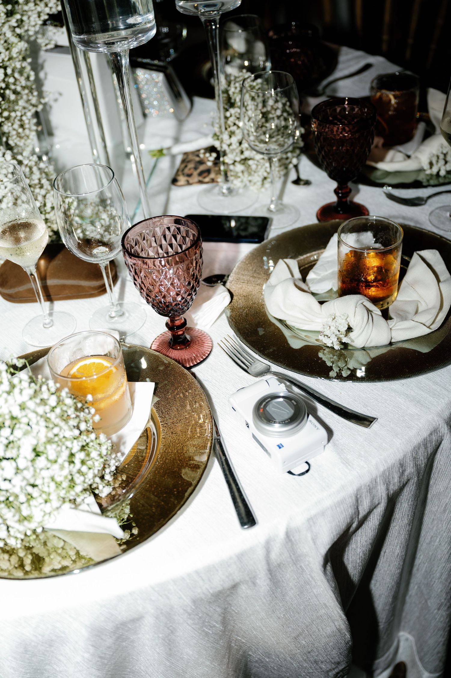 Elegant table setting with vintage purple glassware, white flowers, and candlelight creating a romantic atmosphere.