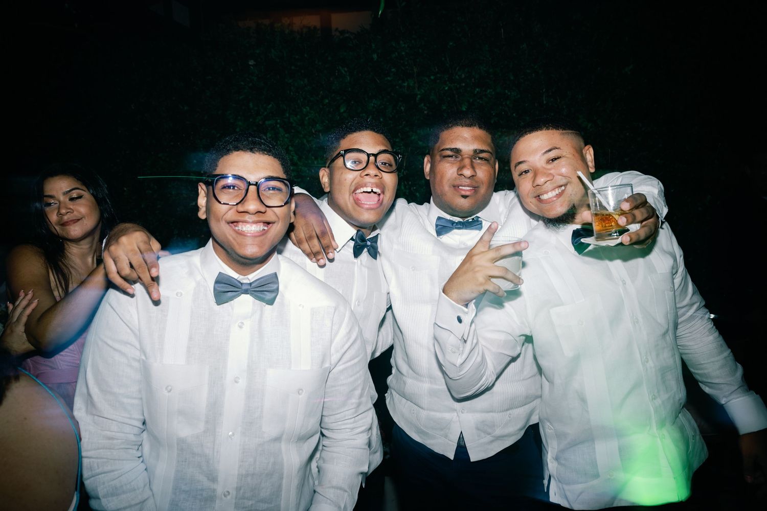 Group of people wearing white dress shirts and bow ties smiling together at a formal event.