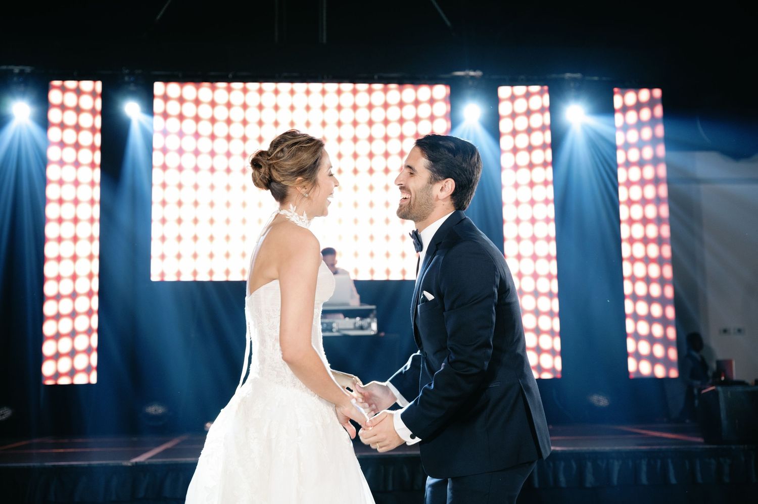 Couple sharing a romantic dance moment under dramatic lighting with glowing red and white backdrop.