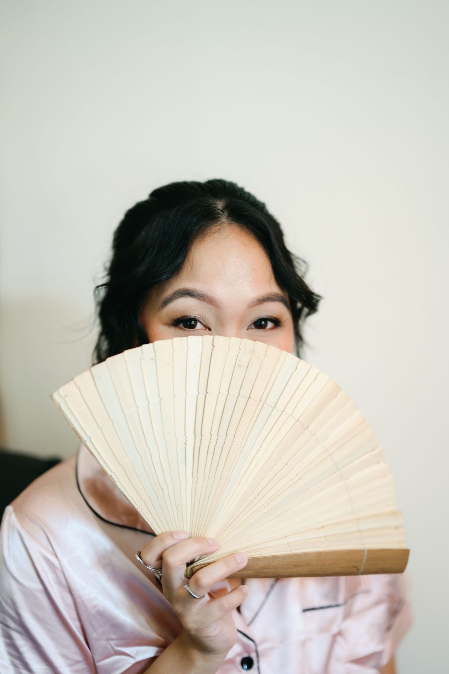 A series of artistic photos showing a traditional paper fan being used to partially cover the face in a playful manner.