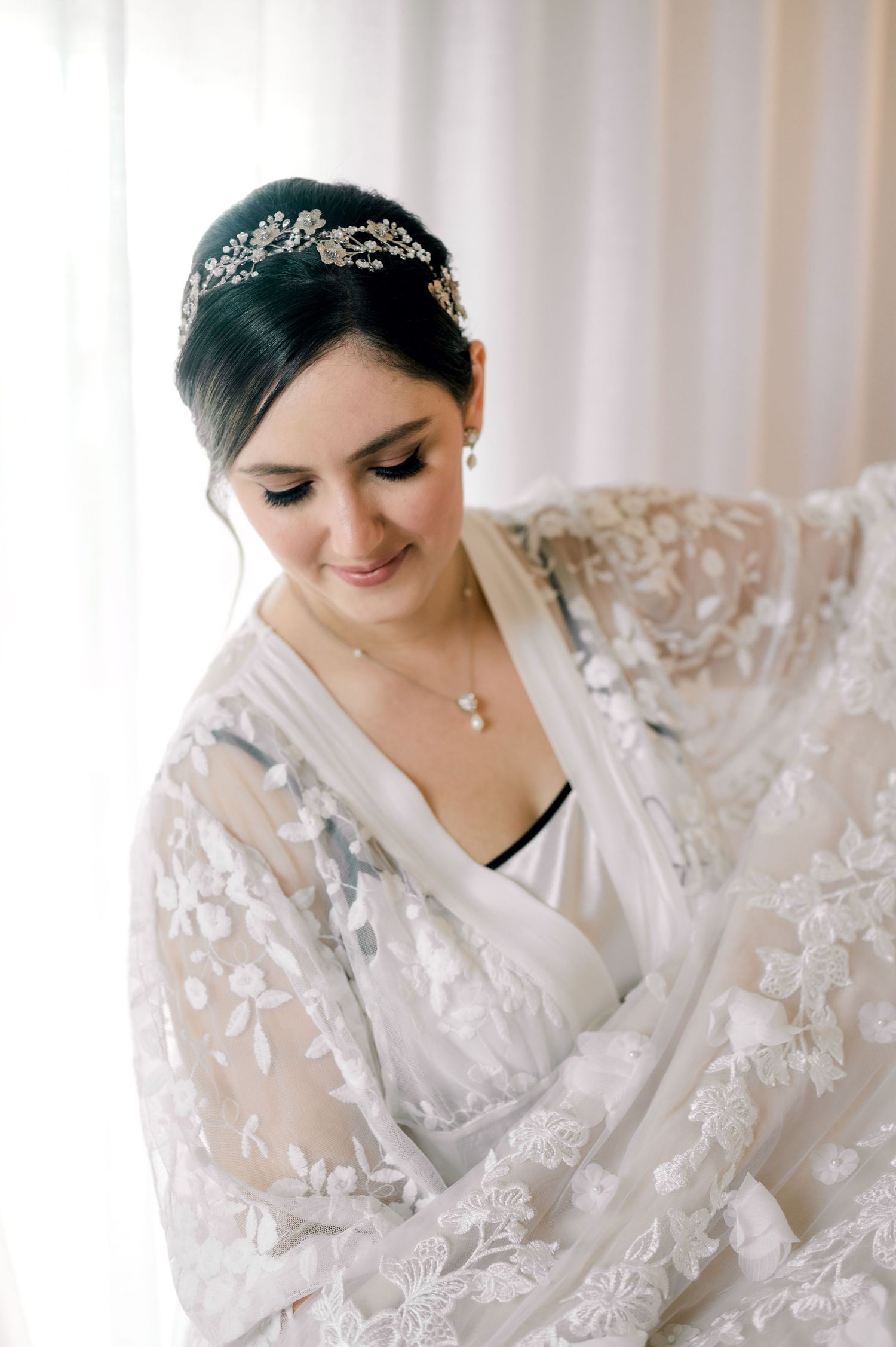A close-up view of delicate white lace bridal robe details against a light background.