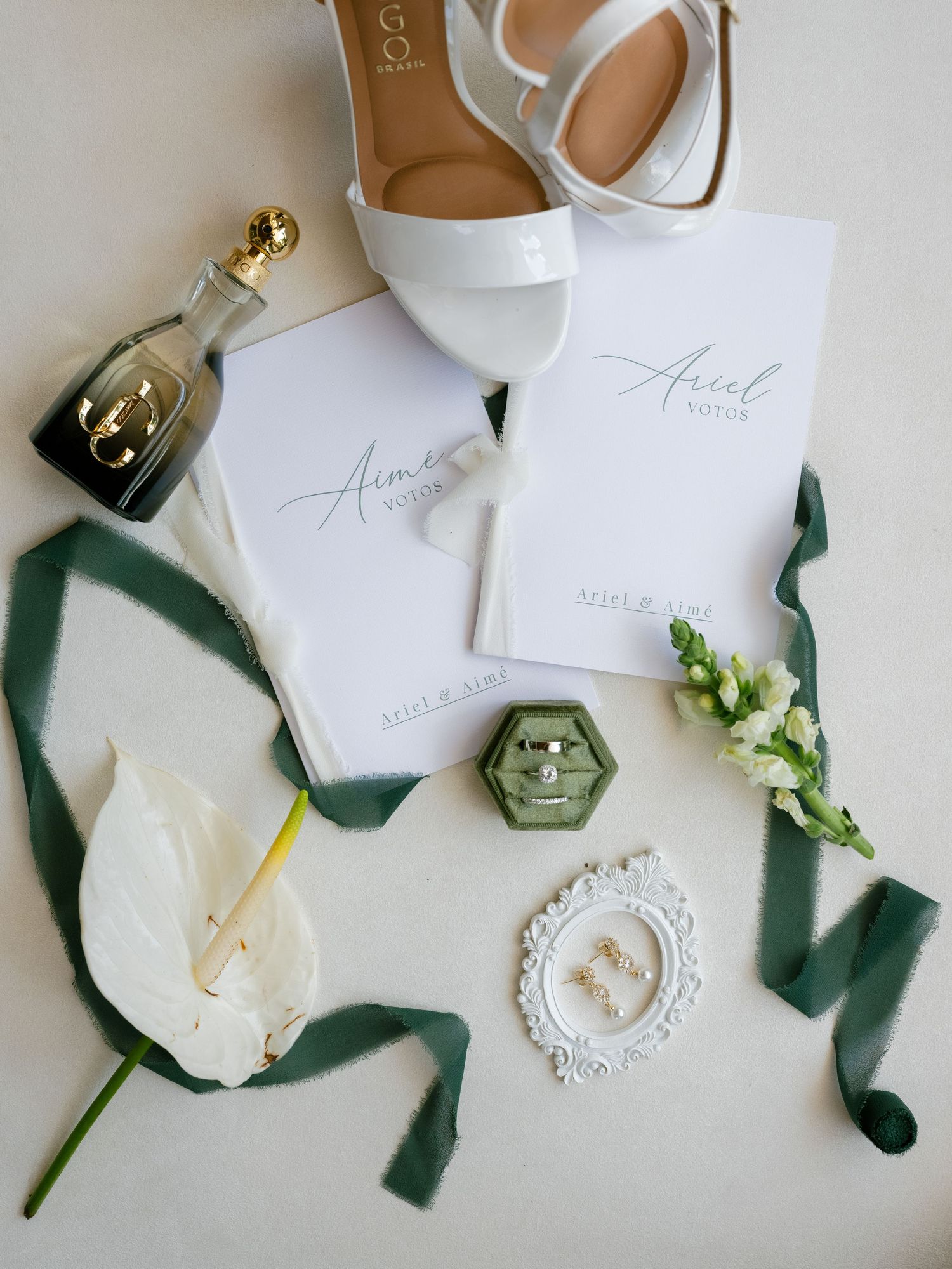 Wedding details flatlay with white flowers, velvet ribbons, and elegant stationery on light background.