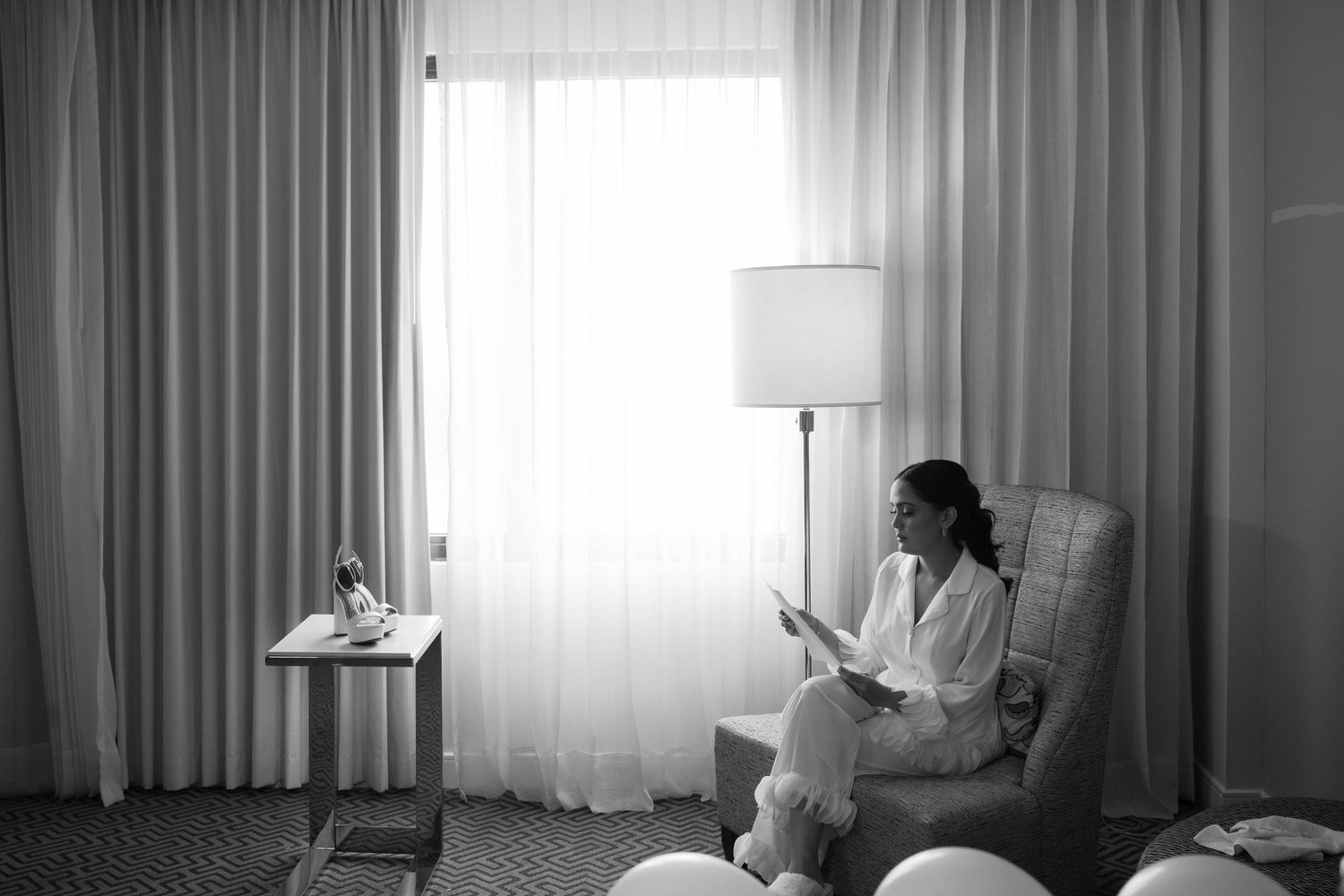 A series of four black and white photographs showing someone reading by a window in a room with curtains.