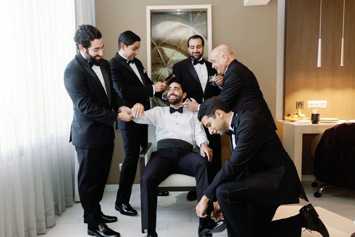 A sequence of wedding preparation moments shows groomsmen helping each other get ready in formal attire.