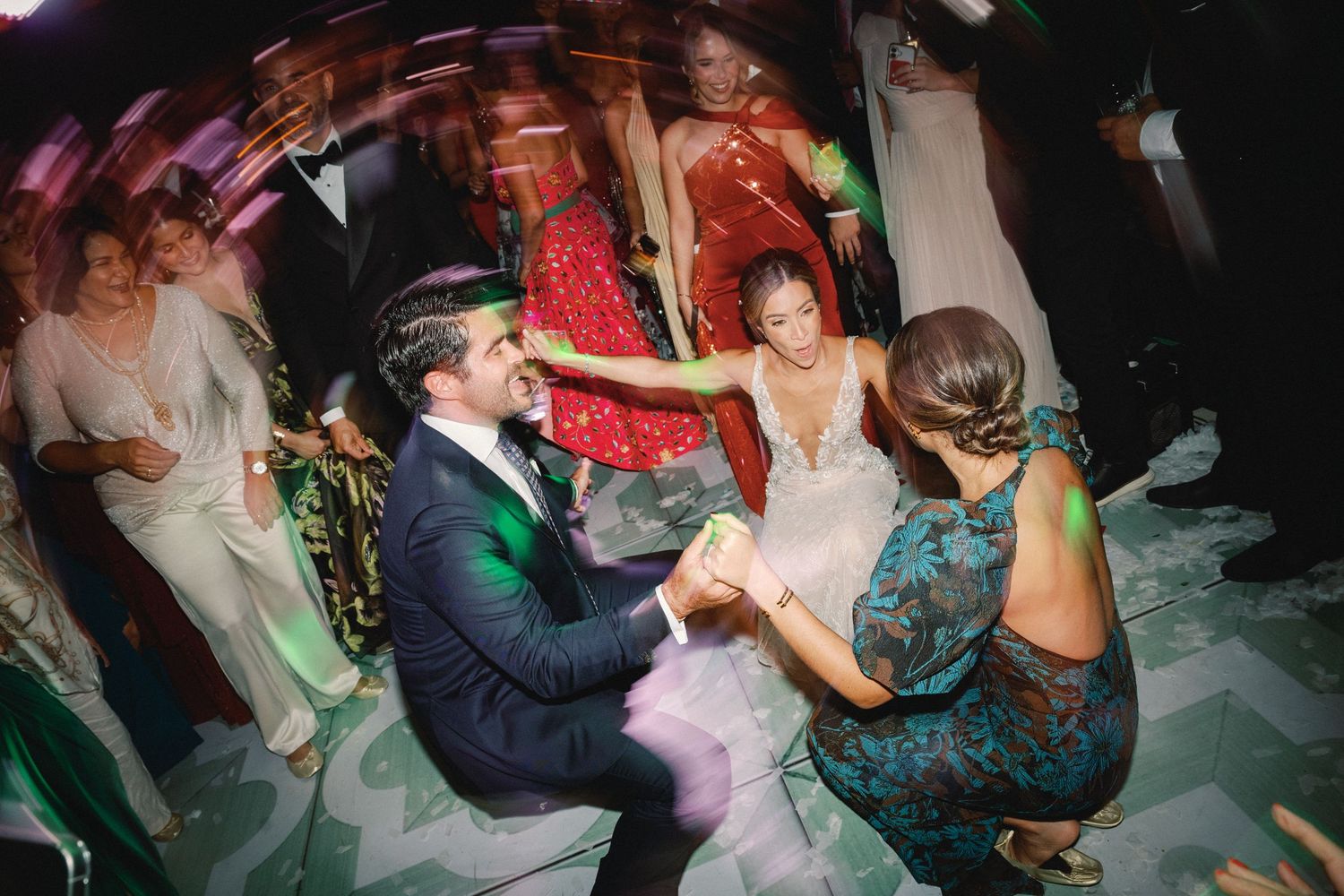 A group of people dancing and celebrating at a lively party with colorful lighting and festive atmosphere.
