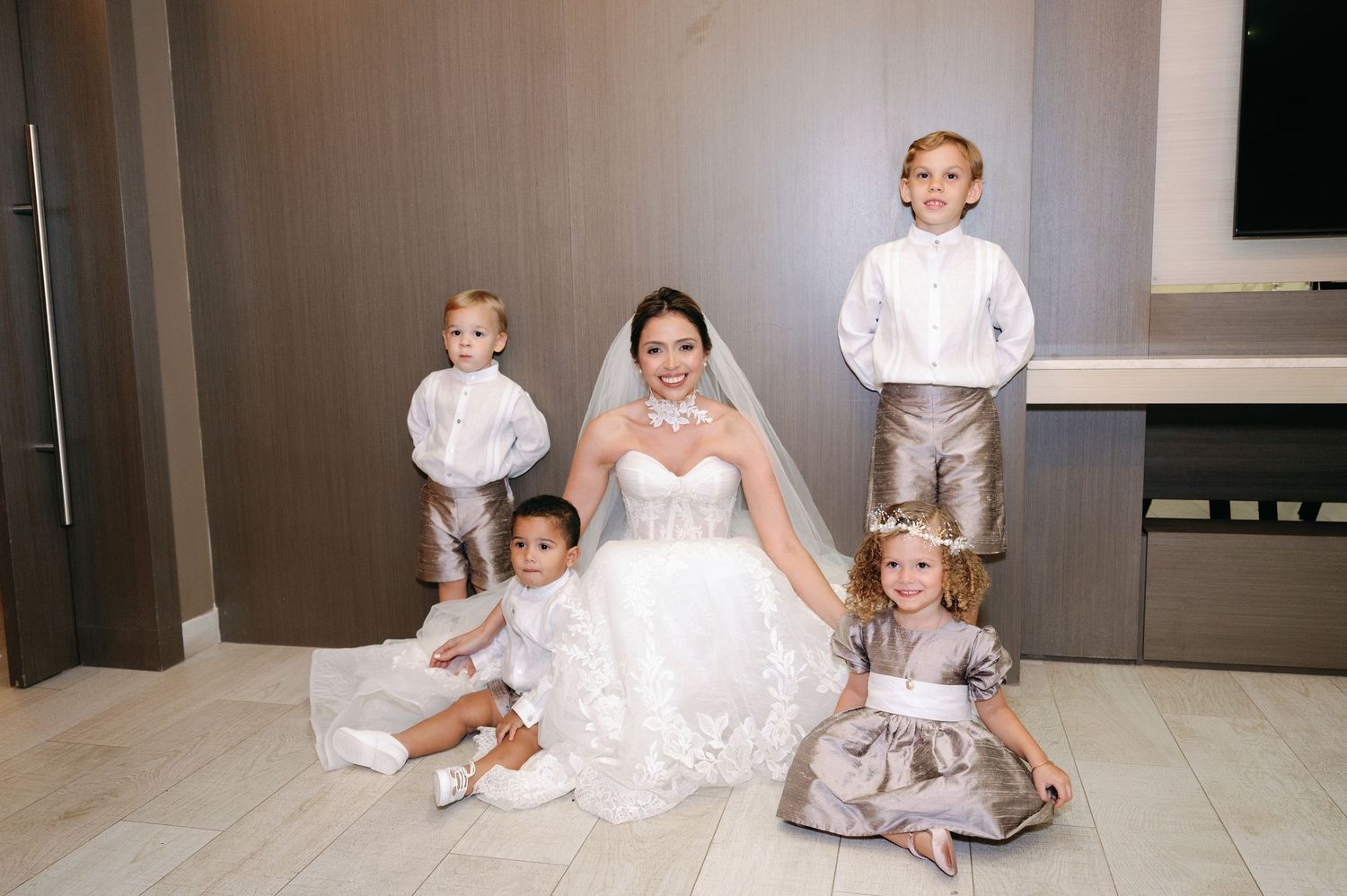 Wedding party members in white dresses seated on the floor for formal portraits.