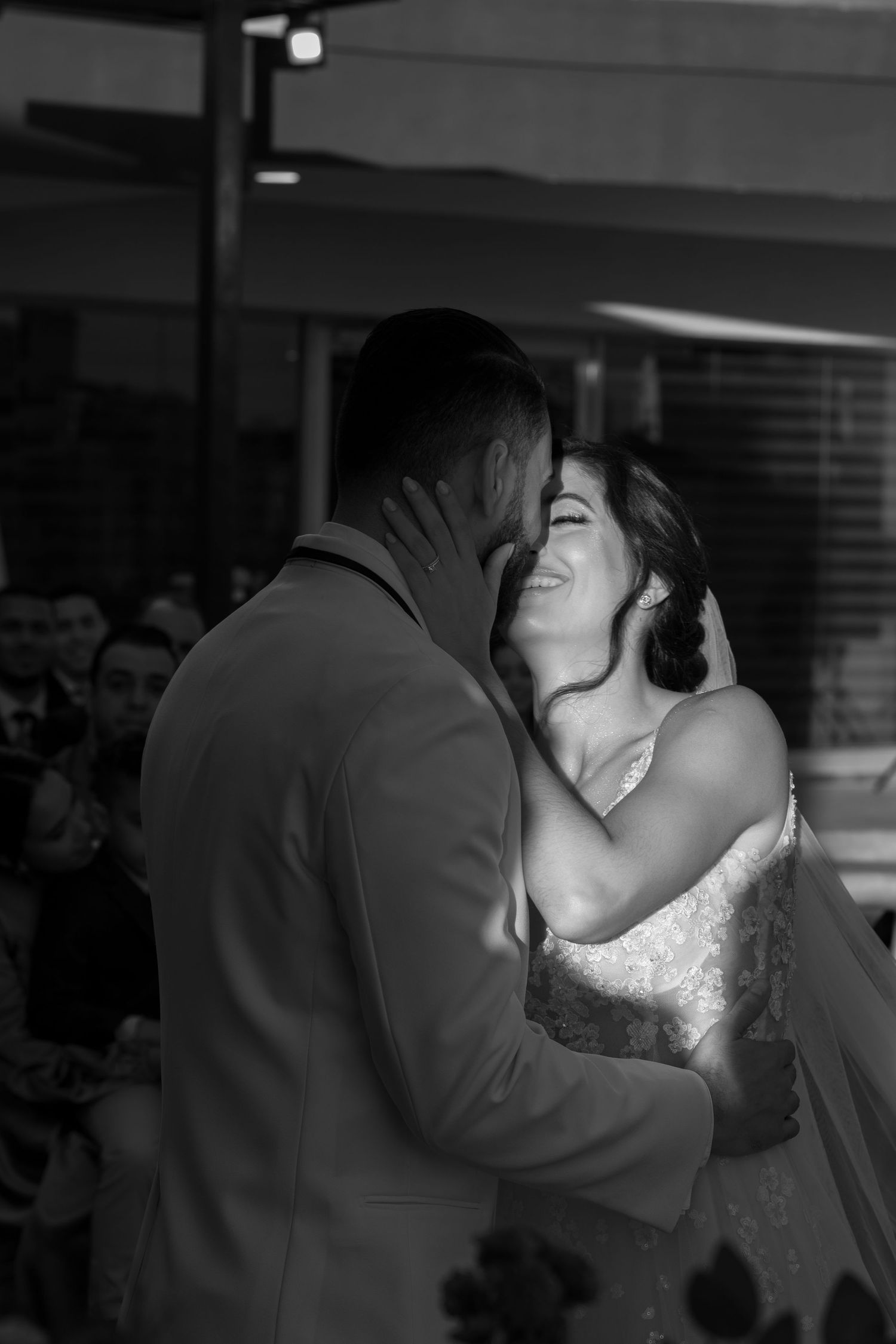 A romantic black and white wedding photo captures a couple's first kiss as newlyweds.