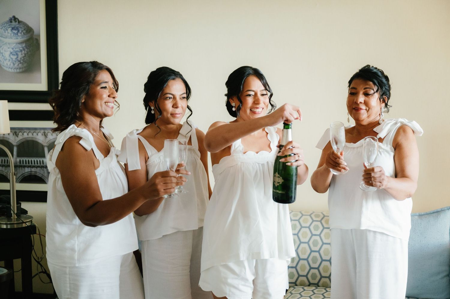 Four people in white outfits share laughter and drinks together in a candid photo sequence.