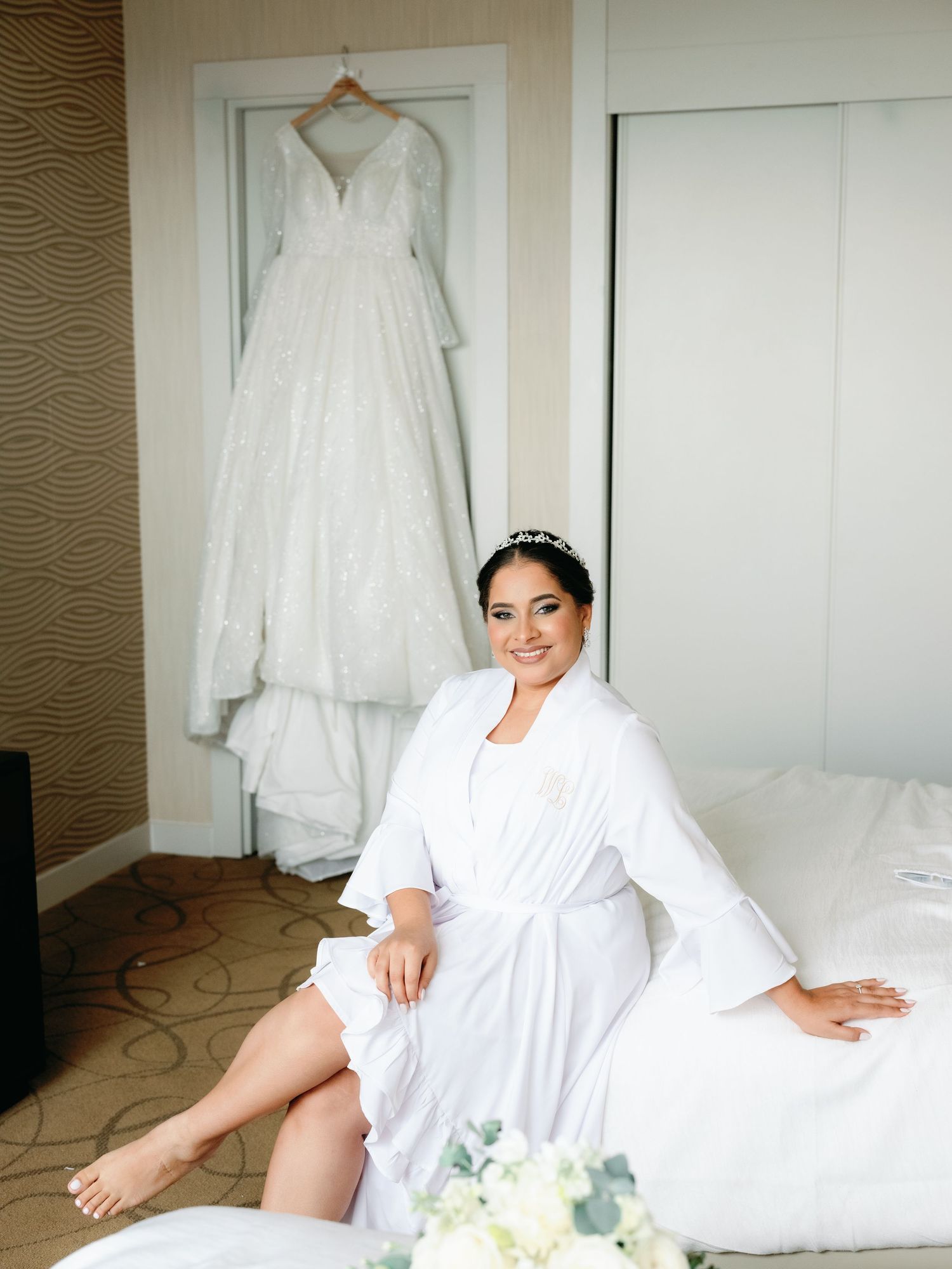 A series of wedding preparation photos showing white bridal robes and gowns hanging and arranged in a bright hotel room.