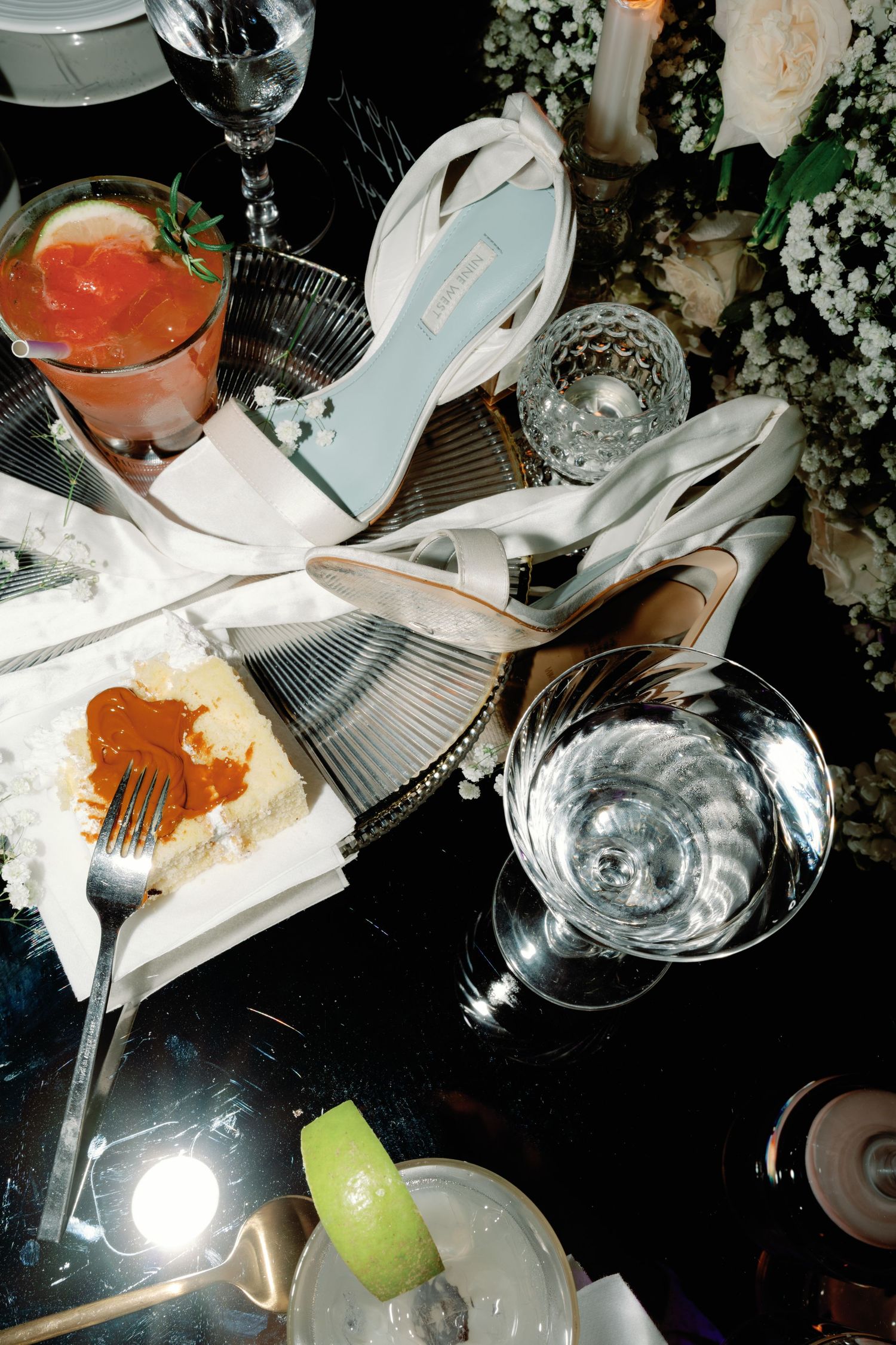 Messy table setting with empty plates, glasses, and scattered dining utensils in dim lighting.