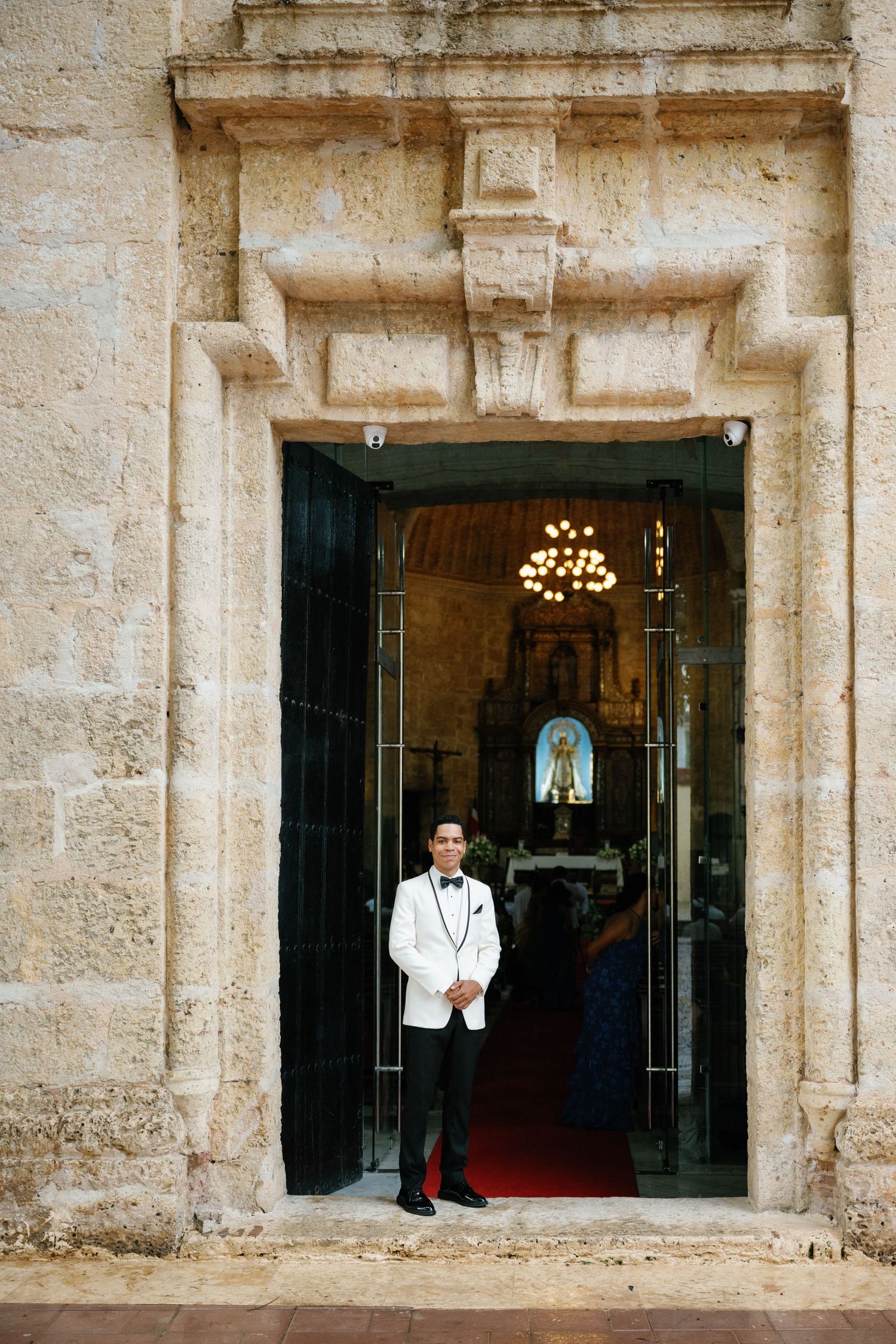 Three arched stone doorways of a historic building with figures standing in formal attire.
