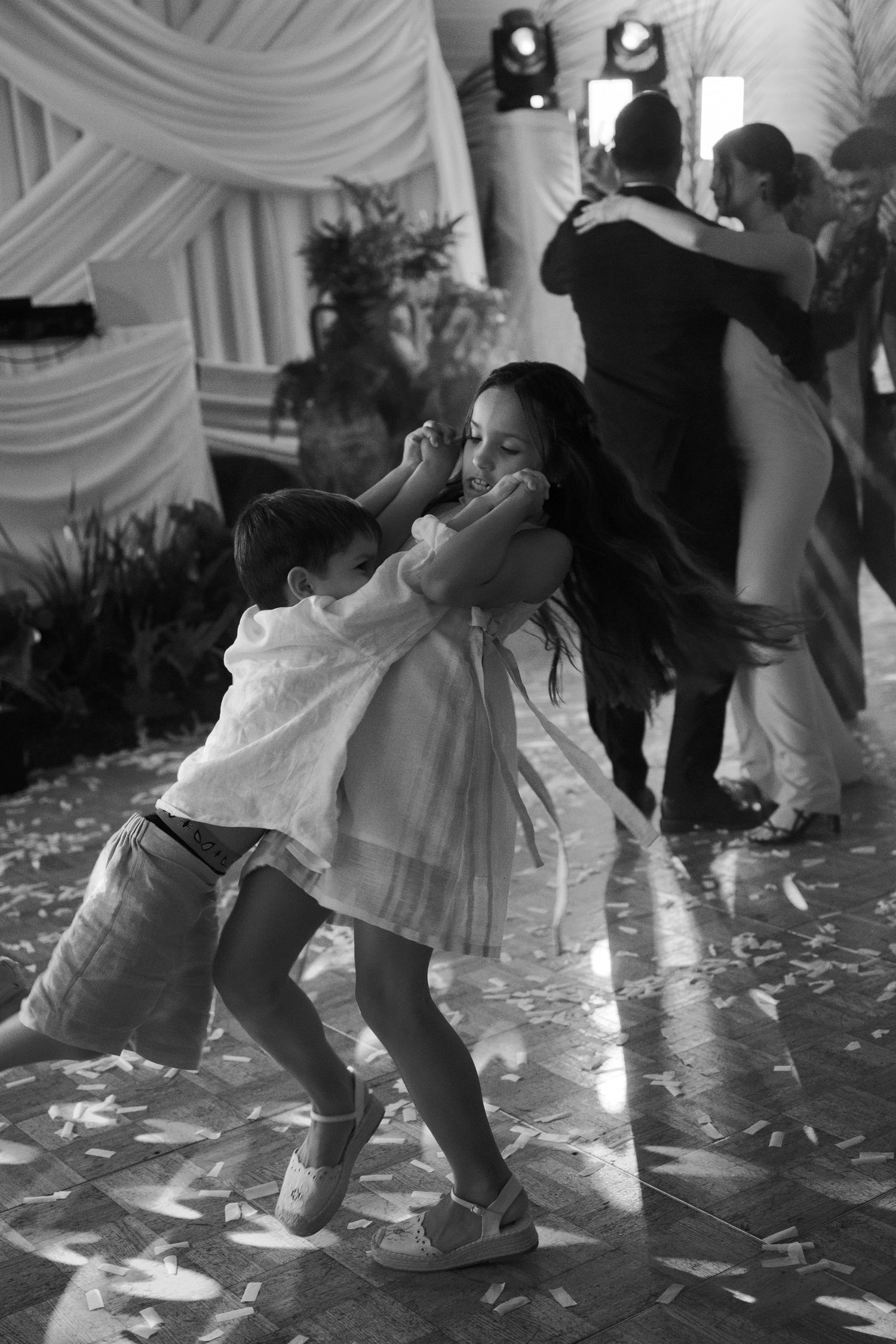 Black and white photo of dancers' feet moving across a petal-covered dance floor.