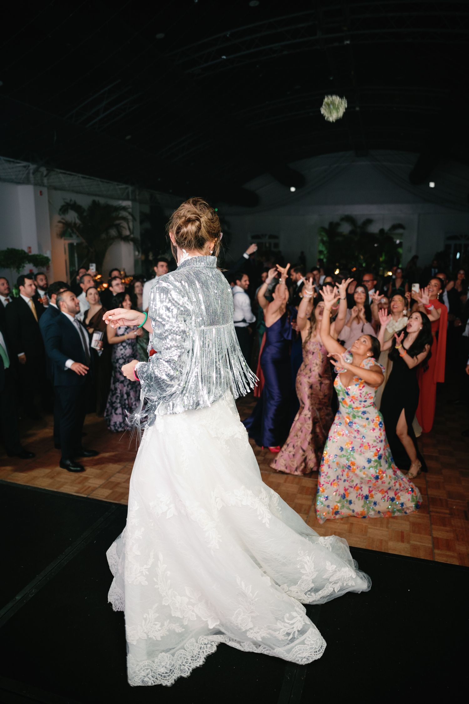 A dance party at a wedding reception with guests dancing under sparkling lights and decorative ceiling.