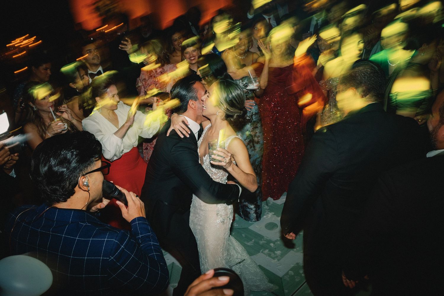 Blurred motion shot of a crowded dance floor at night with colorful lights creating an energetic party atmosphere.