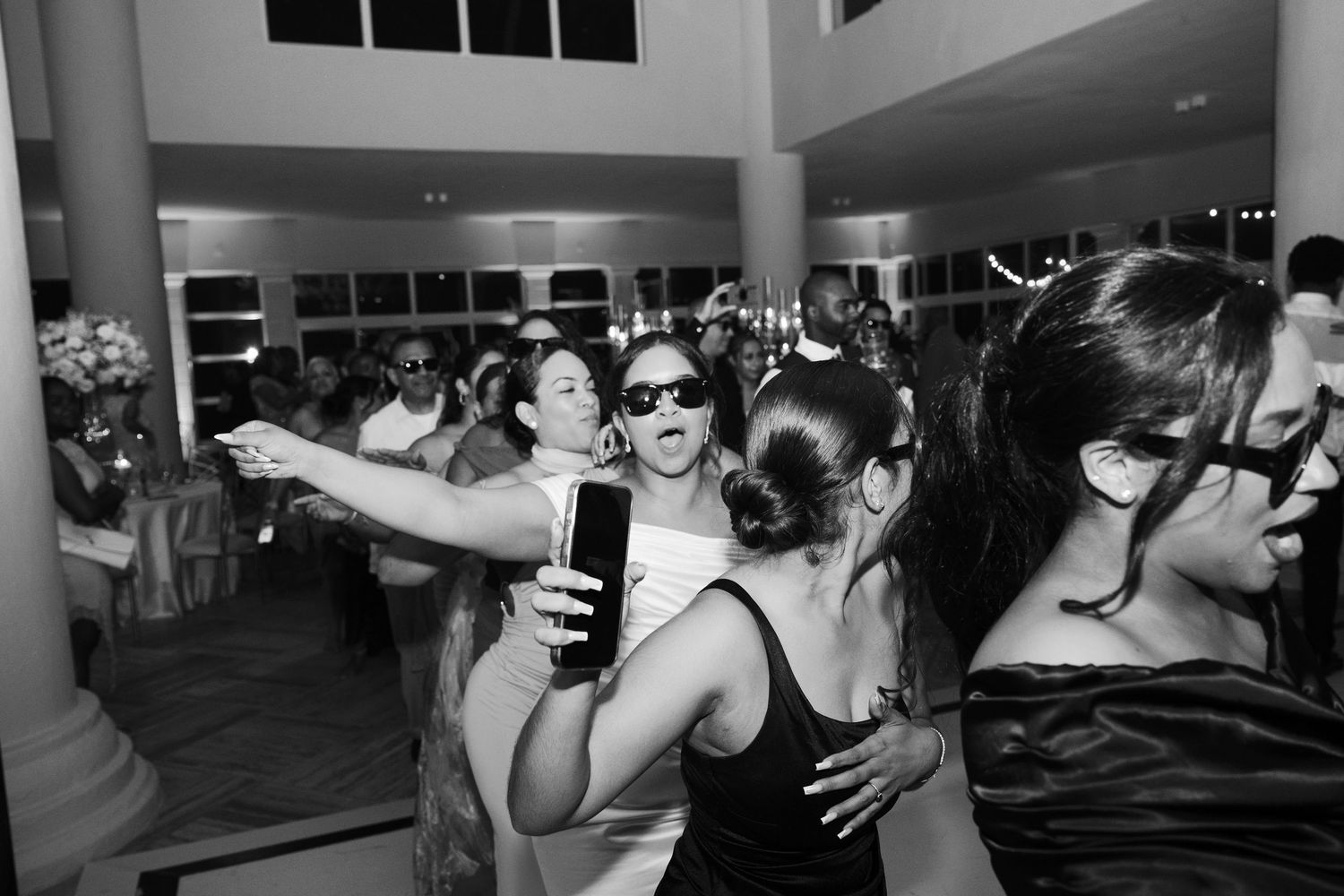 Wedding guests dance and celebrate on a dimly lit dance floor during an energetic reception party.