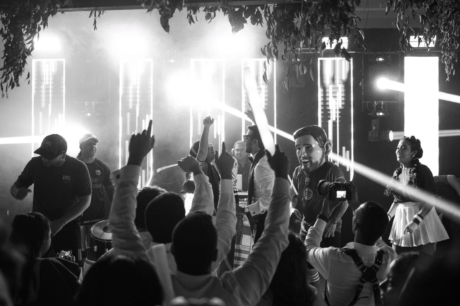 Concert crowd silhouettes dance with hands raised under dramatic lighting at a nightclub performance.