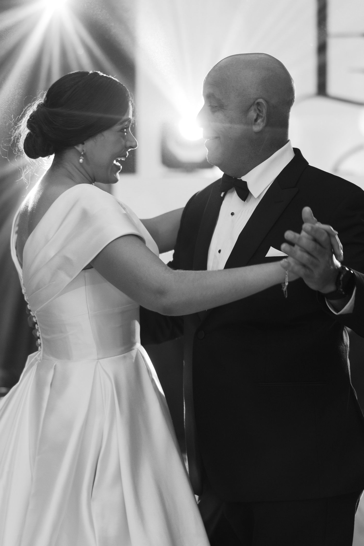 A black and white sequence of dance moves between a bride in white dress and groom in tuxedo.