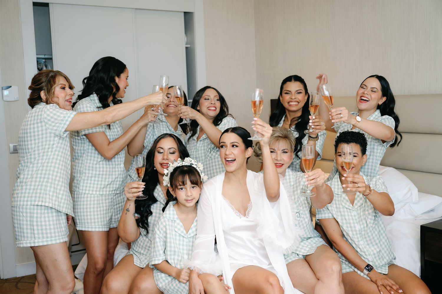 A group of people in matching white and green outfits pose together for a celebratory photo shoot.