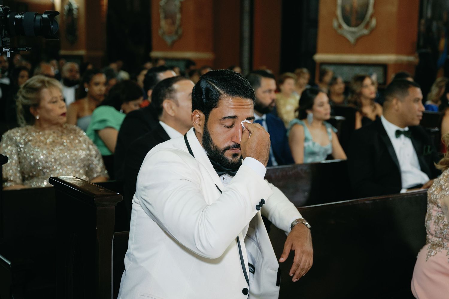 A group of people in formal attire gather around a bar during an elegant evening event.