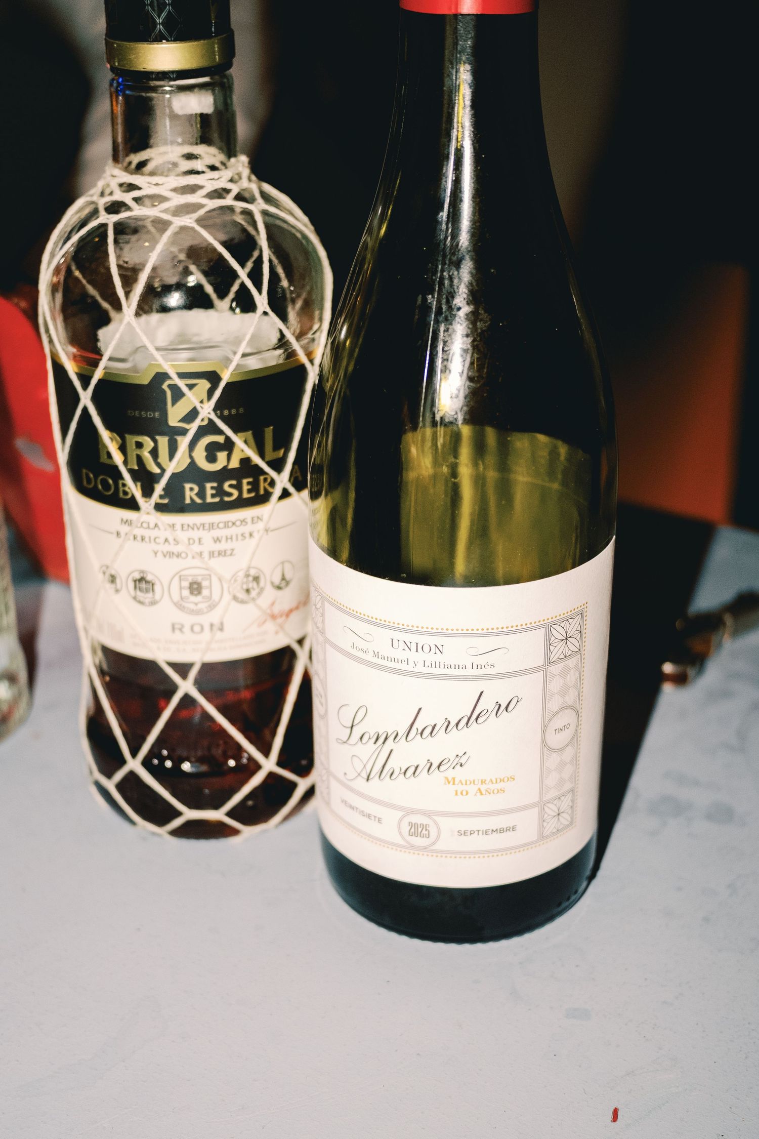 Several wine bottles arranged on a table with decorative netting around their necks.