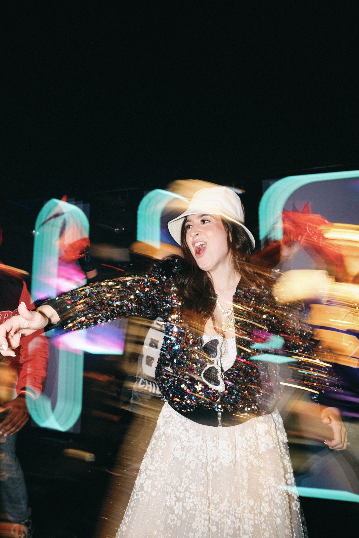 Long exposure photo of a performer in a sparkly dress spinning and dancing with motion blur effects in dark lighting.
