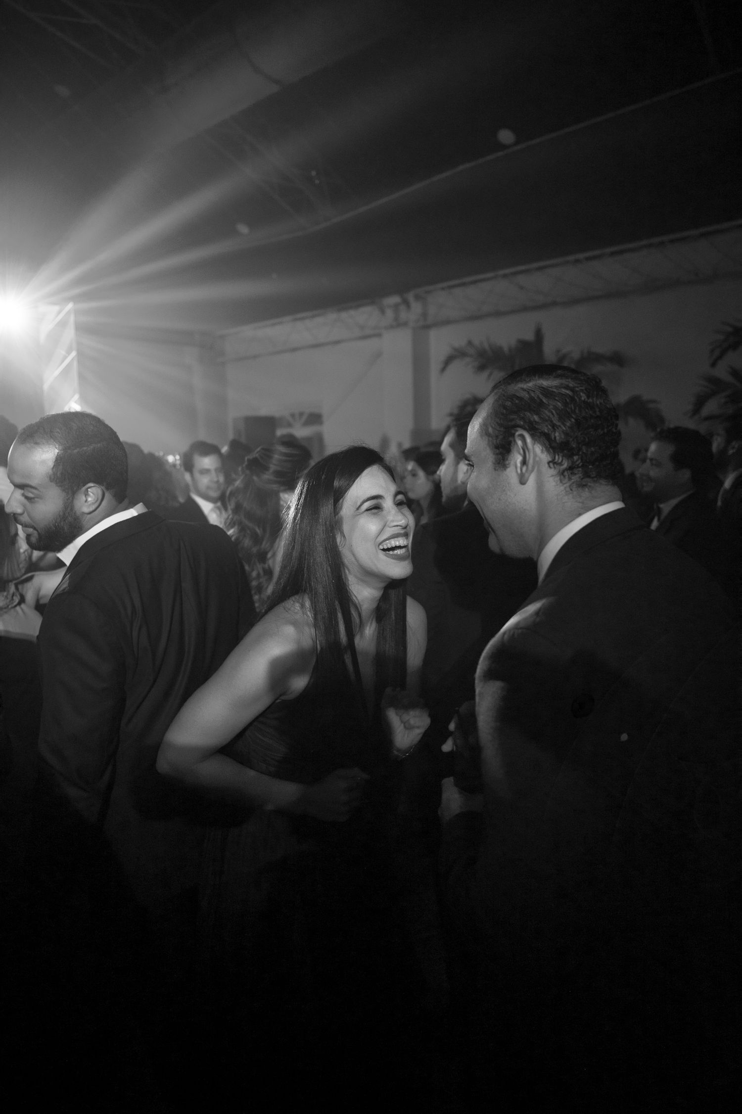 Black and white photo of guests laughing and socializing at an elegant evening party.