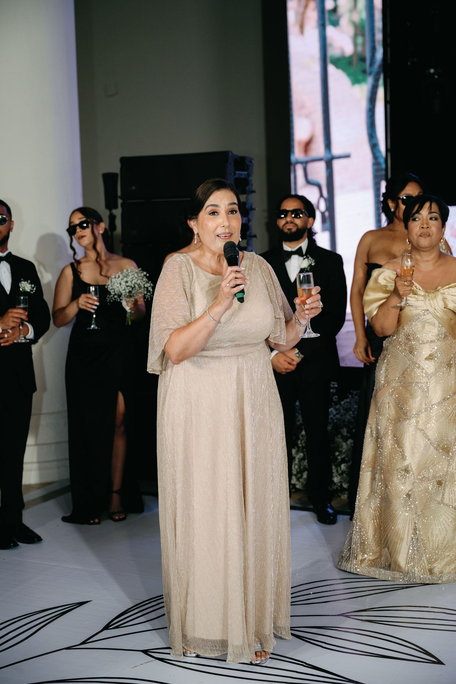 Wedding guests in formal attire raise their glasses in a toast during an elegant celebration.