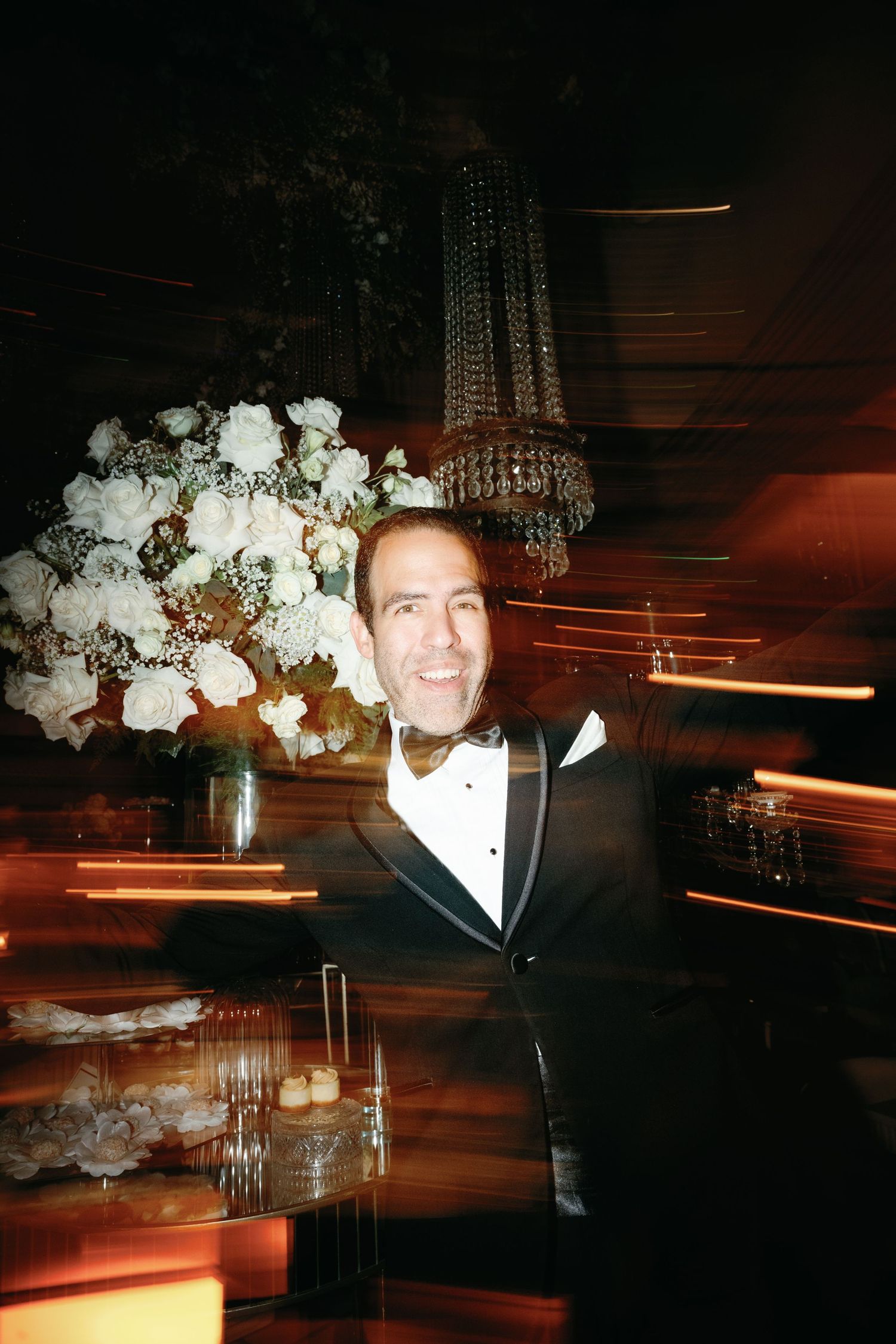 Elegant floral centerpieces with white roses and crystal chandeliers create an upscale ambiance at an evening event.