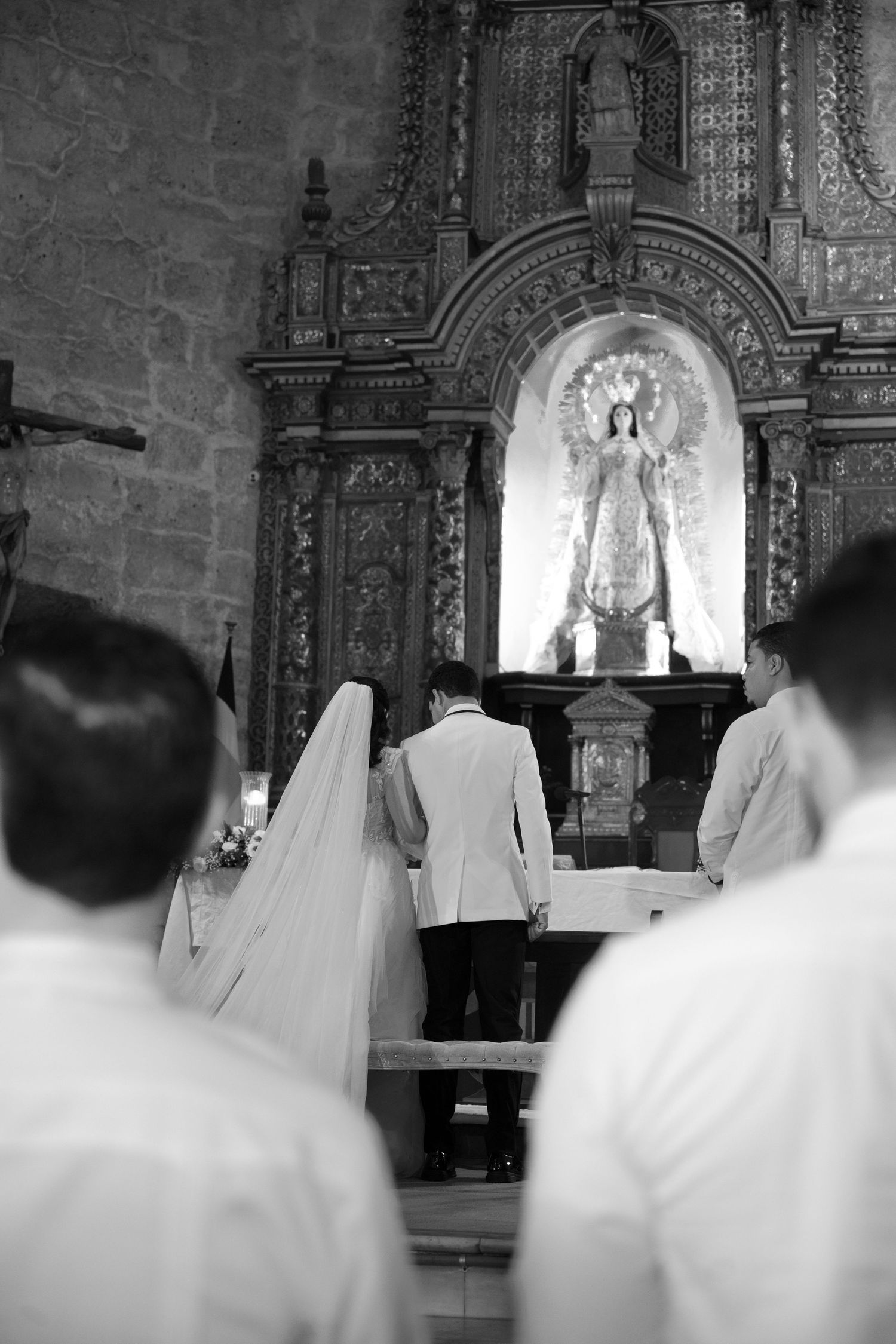 Black and white photo of a traditional church wedding ceremony with attendees in white.