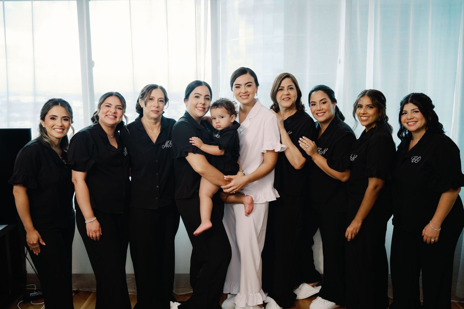 Group wearing black outfits pose together in a bright modern interior space for a professional photoshoot.