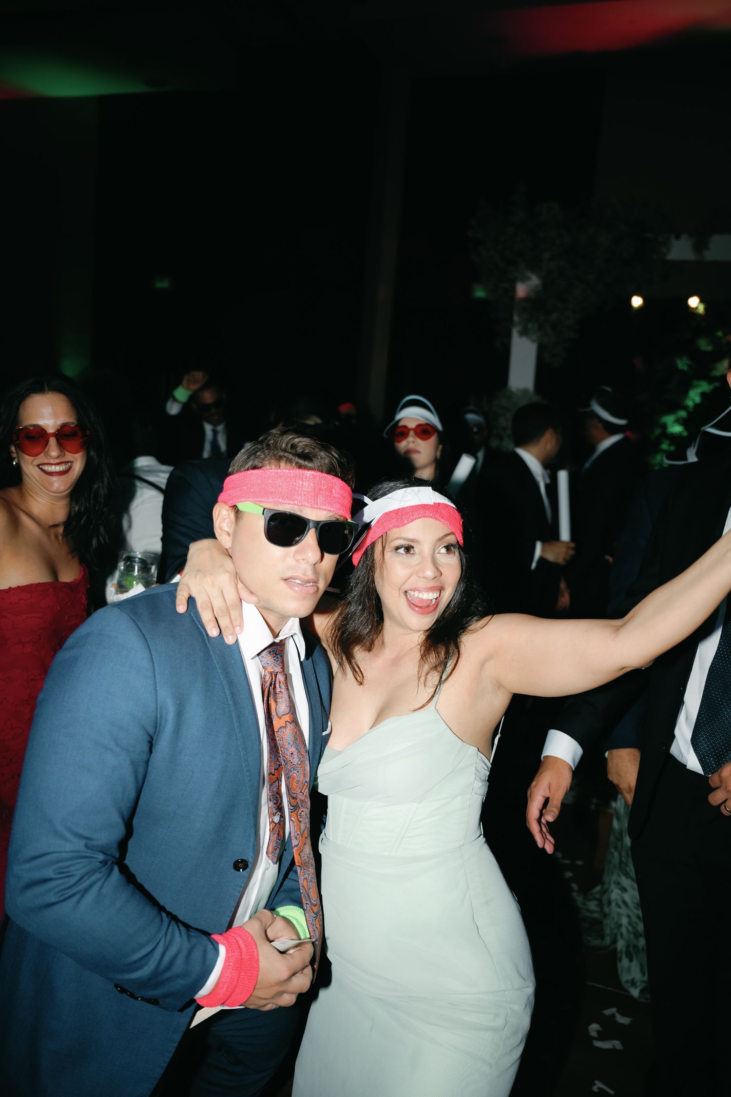 Group of party-goers posing together at a nightclub event wearing sunglasses and casual attire.