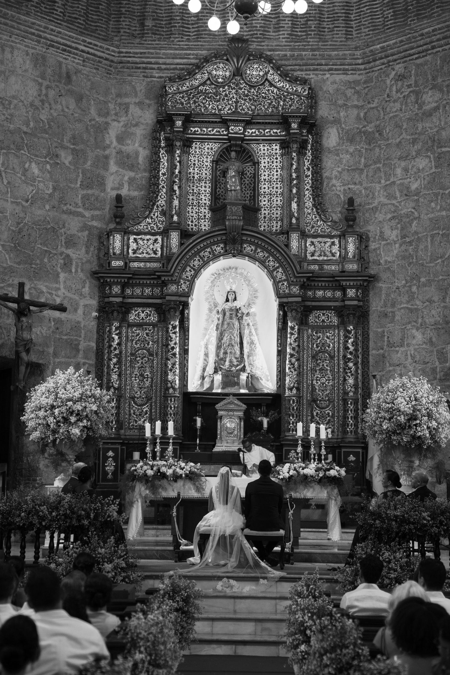 A traditional Catholic church wedding ceremony showing multiple angles of the altar decorated with white floral arrangements.