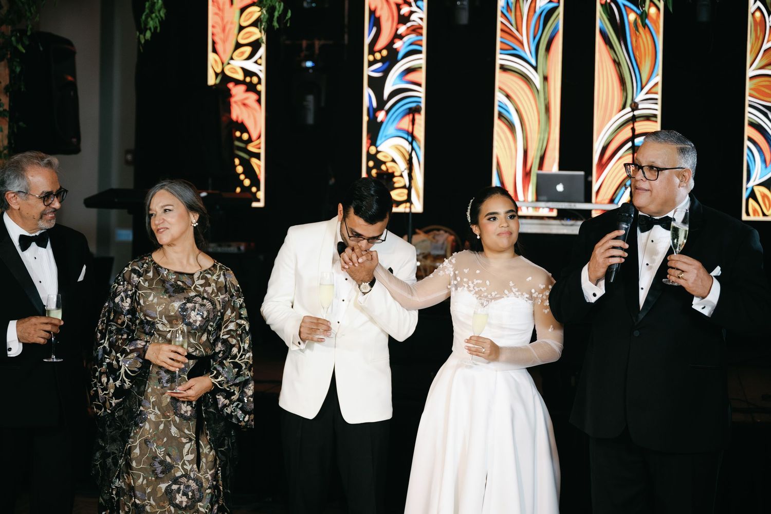 A row of formally dressed guests in black and white attire stand together at an elegant evening event.