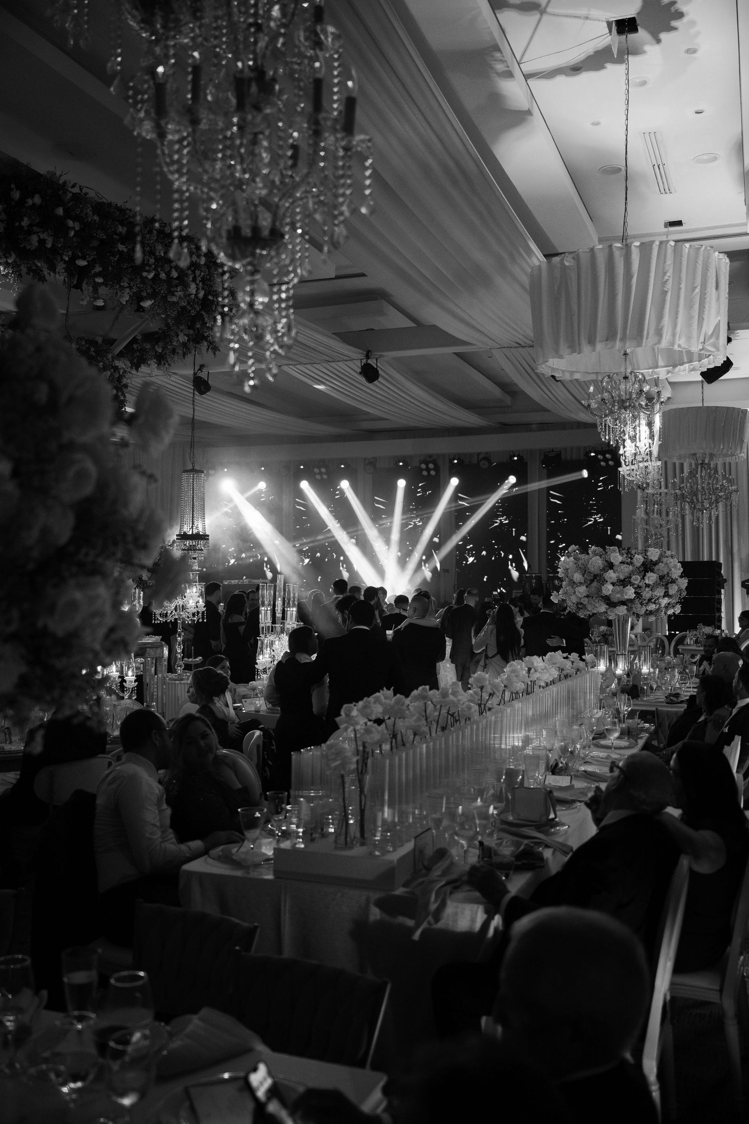 Elegant wedding reception venue with crystal chandeliers and dramatic lighting creating a luxurious atmosphere.