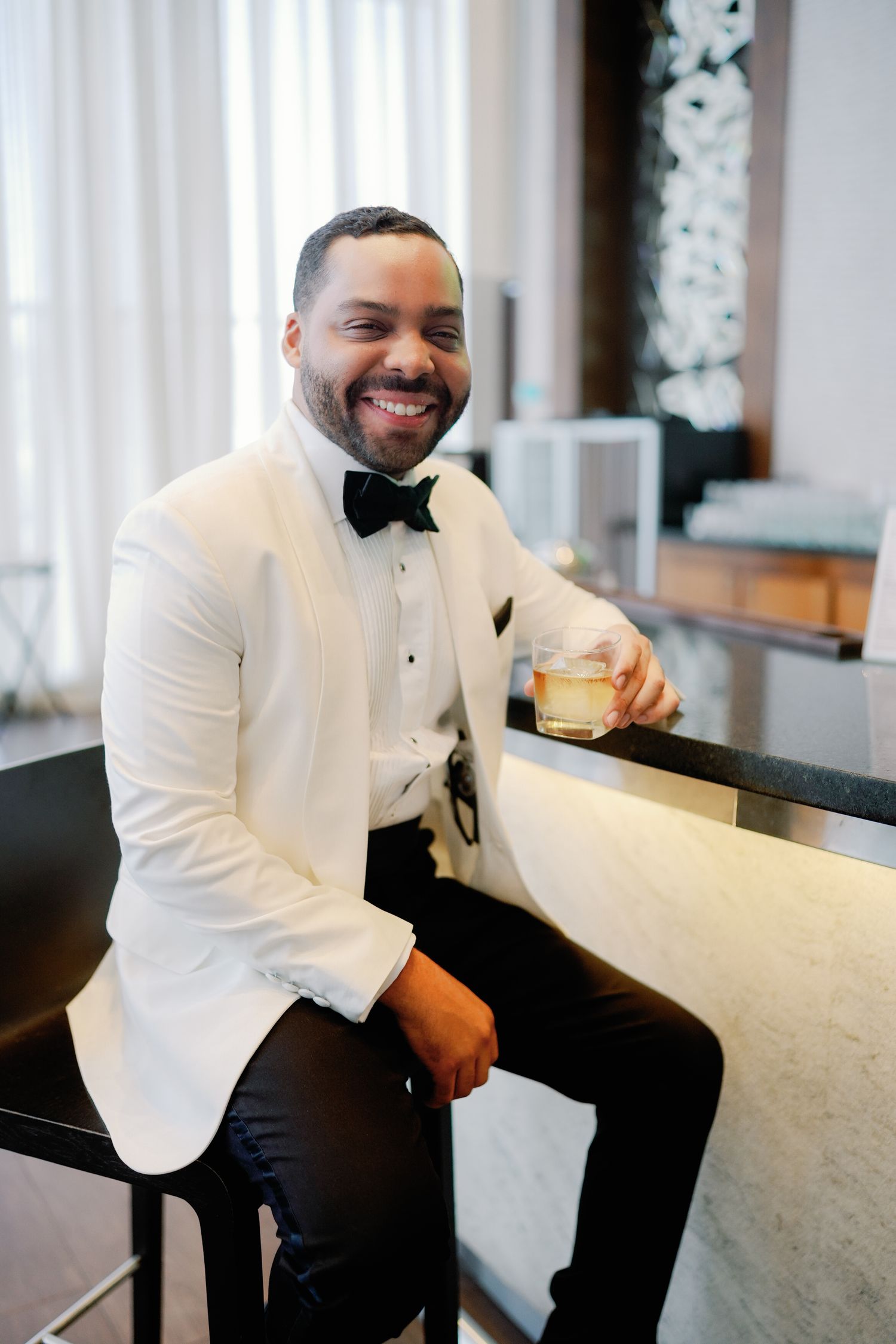 A person in a white blazer jacket sits casually at a bar counter, shown in a series of candid shots.