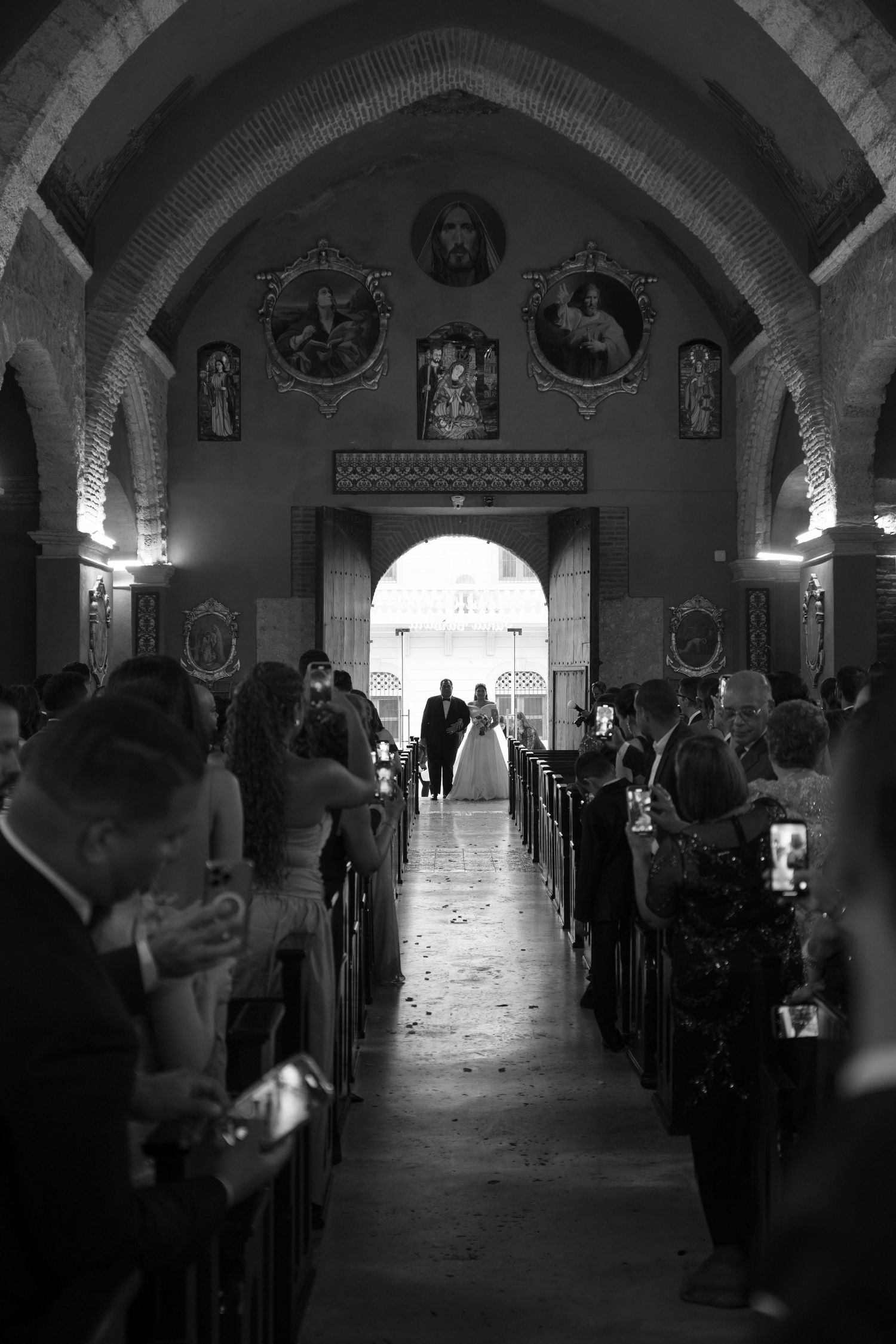 Black and white photo of church interior with arched ceiling and rows of pews in dramatic lighting.
