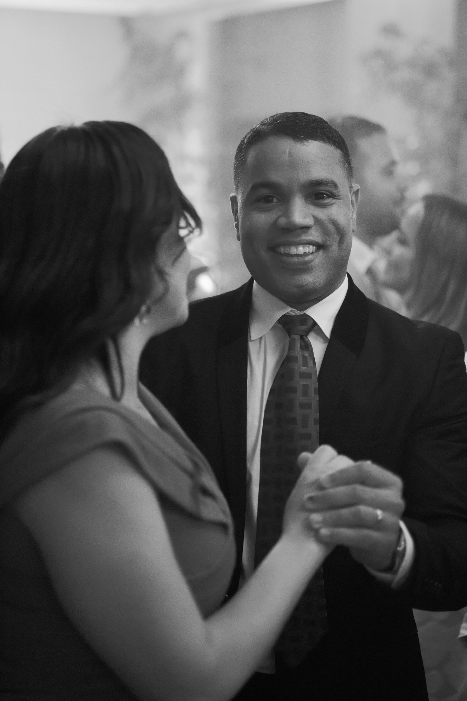 Black and white candid shots of wedding guests laughing and enjoying conversation at a reception.