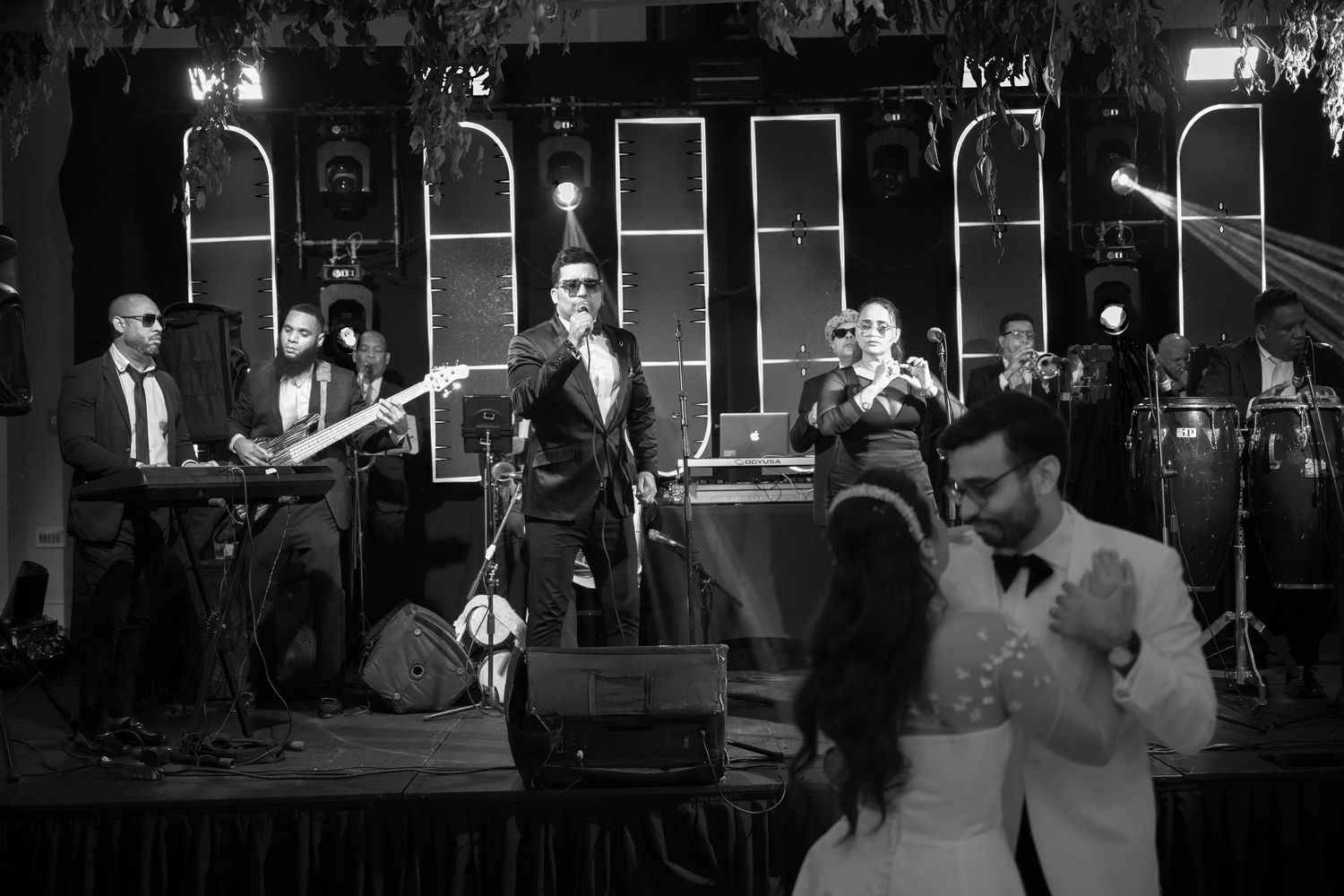 Wedding reception dance floor scene with guests celebrating in a dimly lit venue.