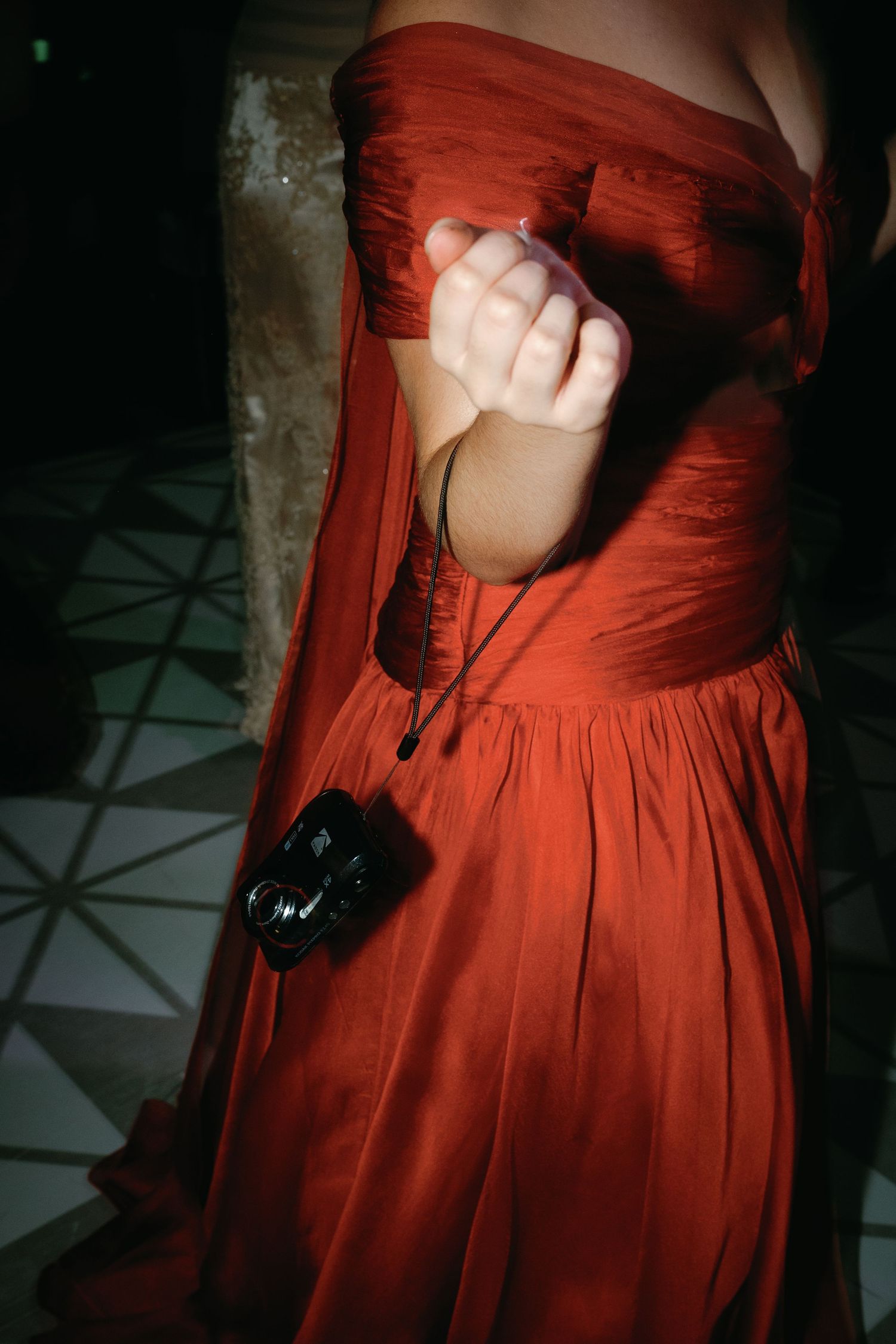 A sequence of photos showing details of a flowing red dress against dark shadows and geometric floor patterns.