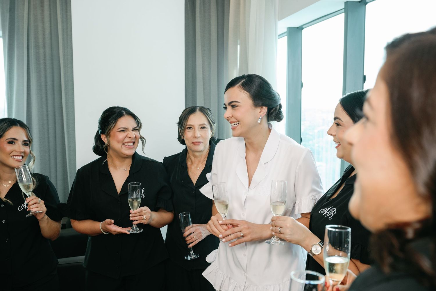 A group of people laughing and socializing together in a bright office setting.