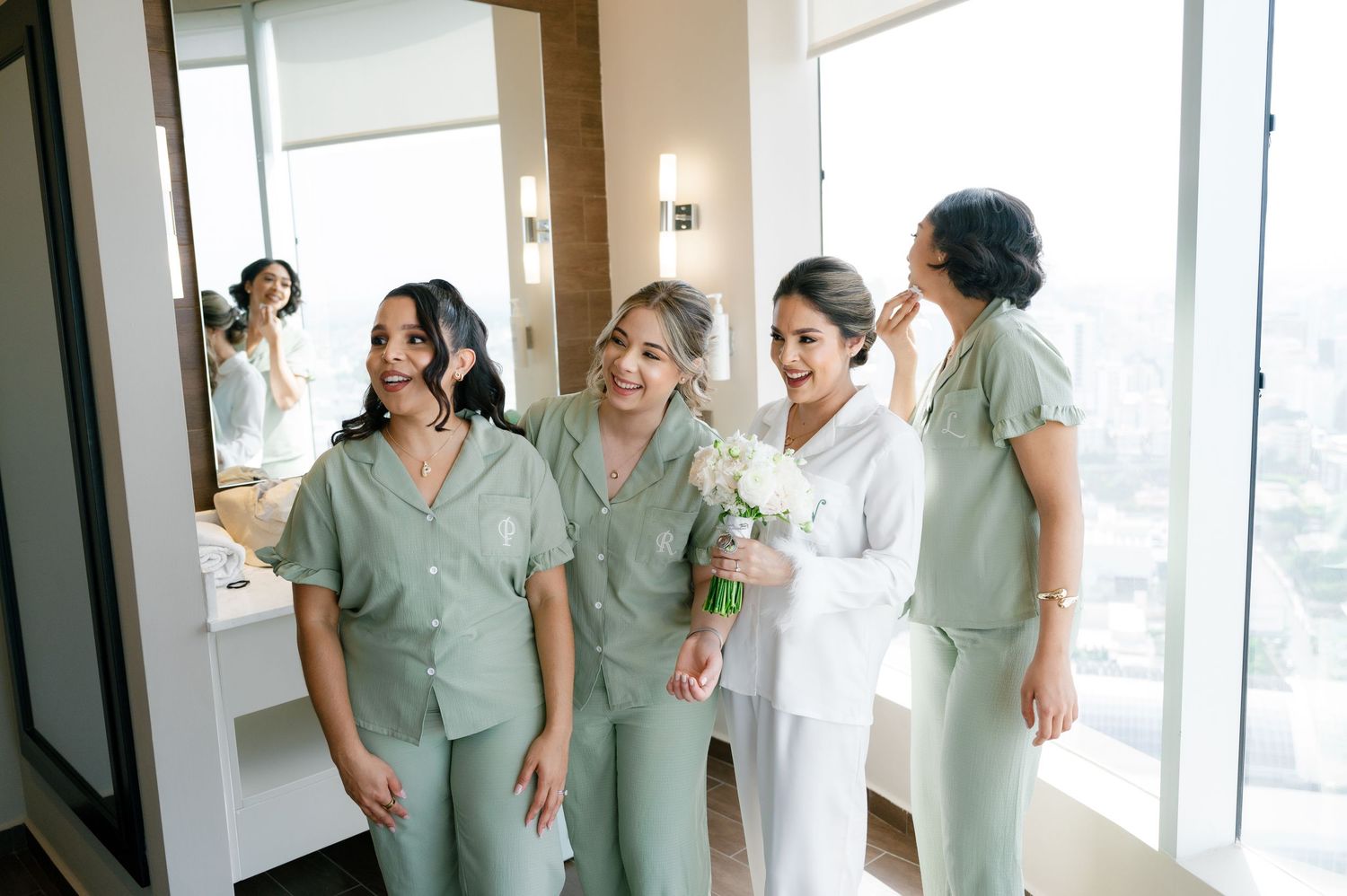 Medical professionals in mint green scrubs gather together in a bright hallway for a candid group moment.