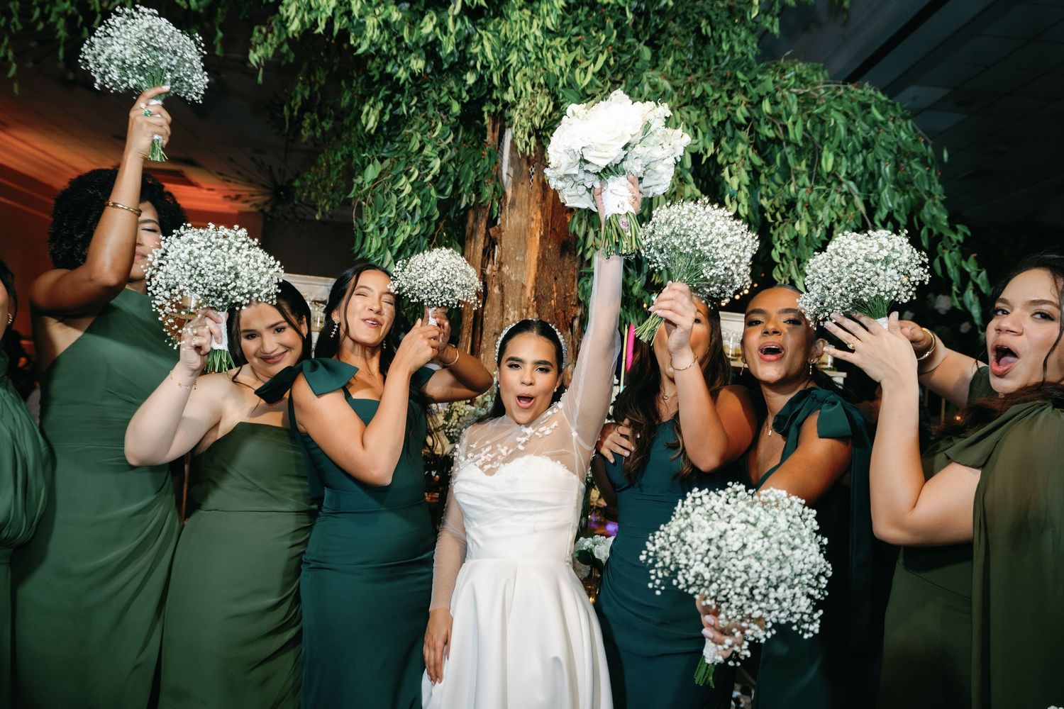 Wedding party members in mint green dresses celebrating with bouquets of baby's breath flowers.