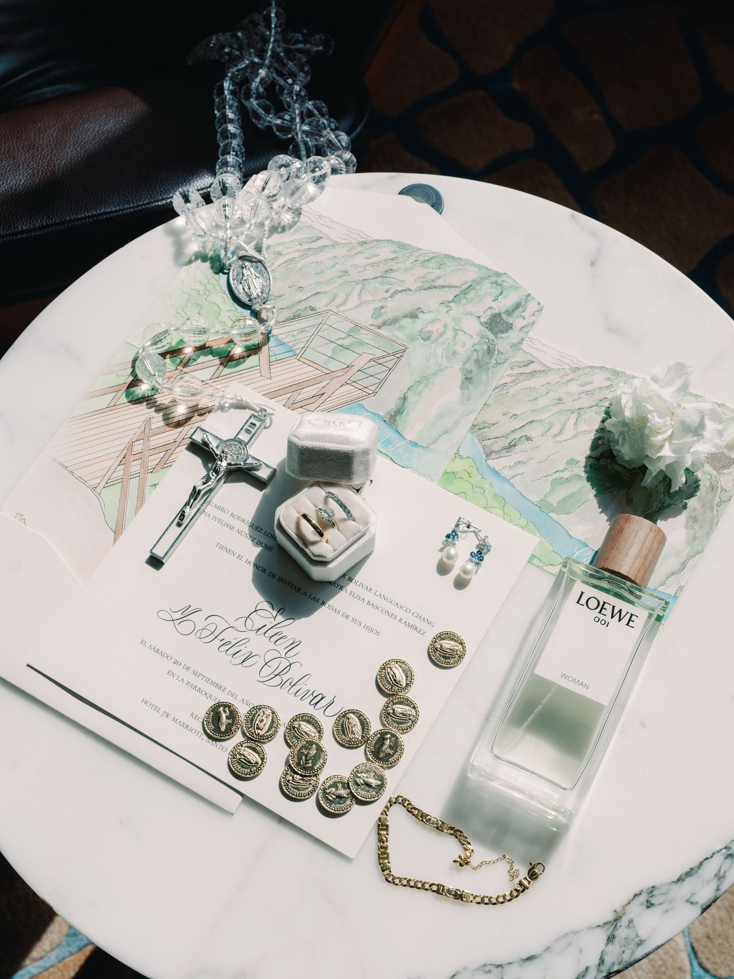 Elegant white and mint green wedding stationery set with gold coins and delicate floral arrangements on a white table.