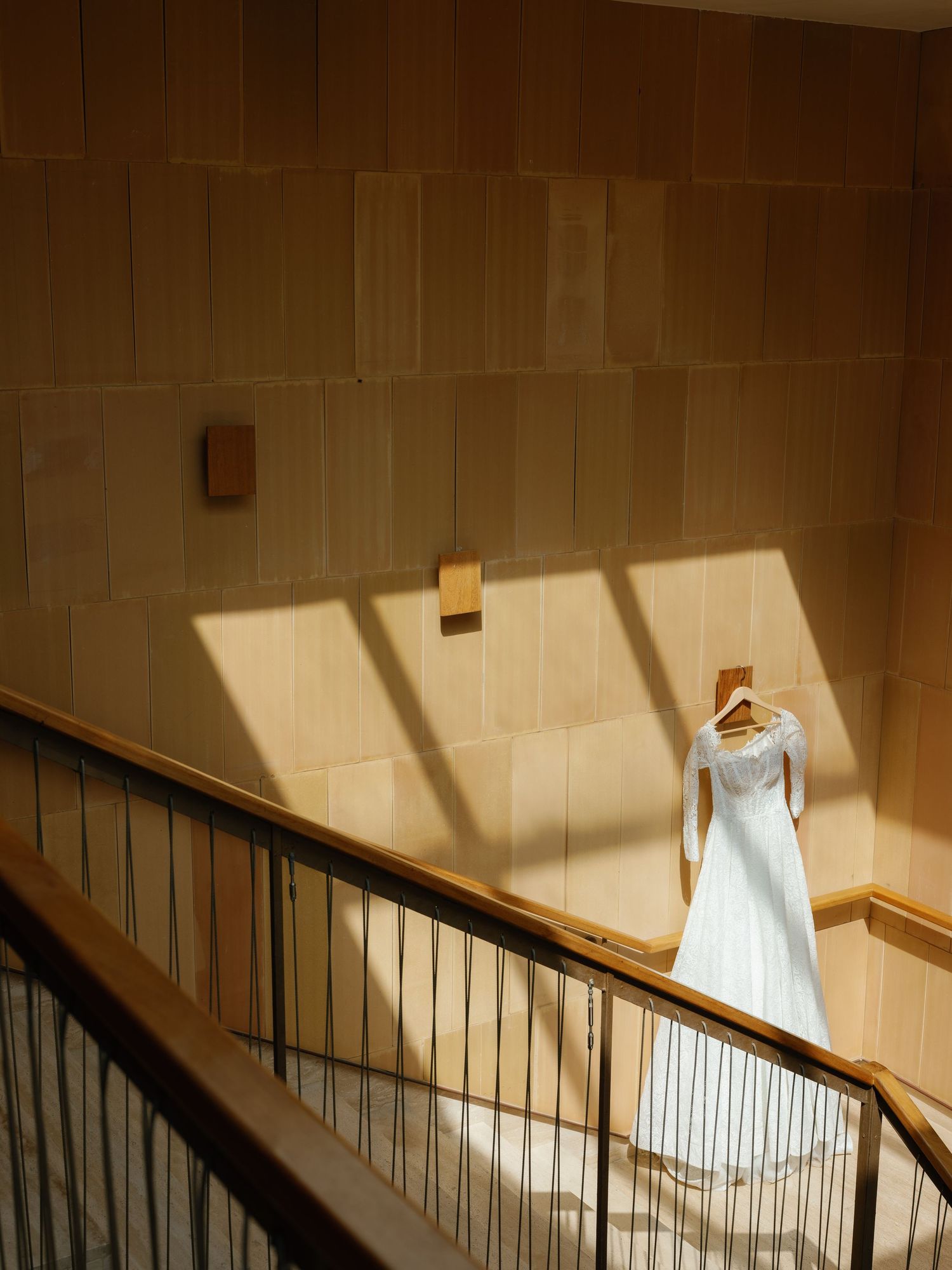 A series of images showing sunlight and shadows cast on a wooden staircase wall with a white dress hanging above.