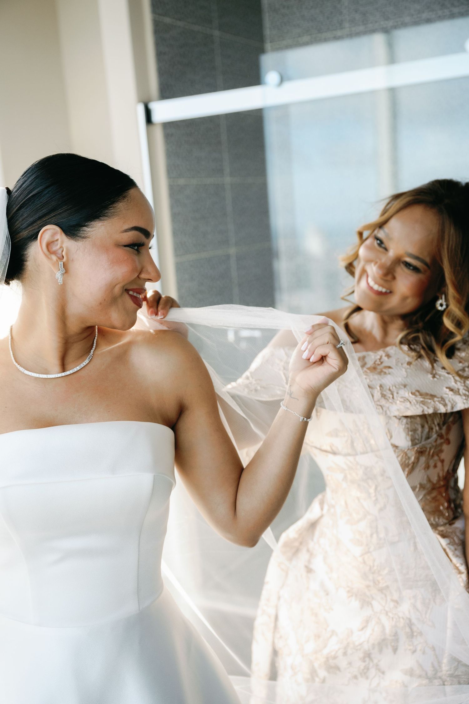Two people share a joyful moment while wearing elegant white dresses.