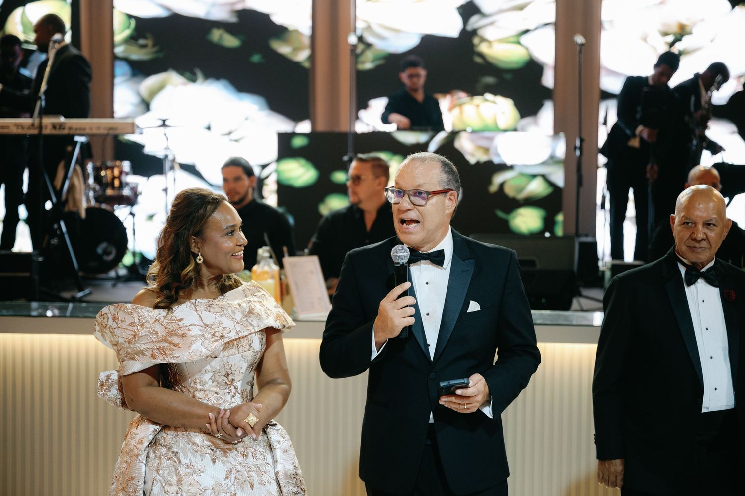 Wedding guests share joyful laughter during an elegant reception celebration in a formal indoor setting.